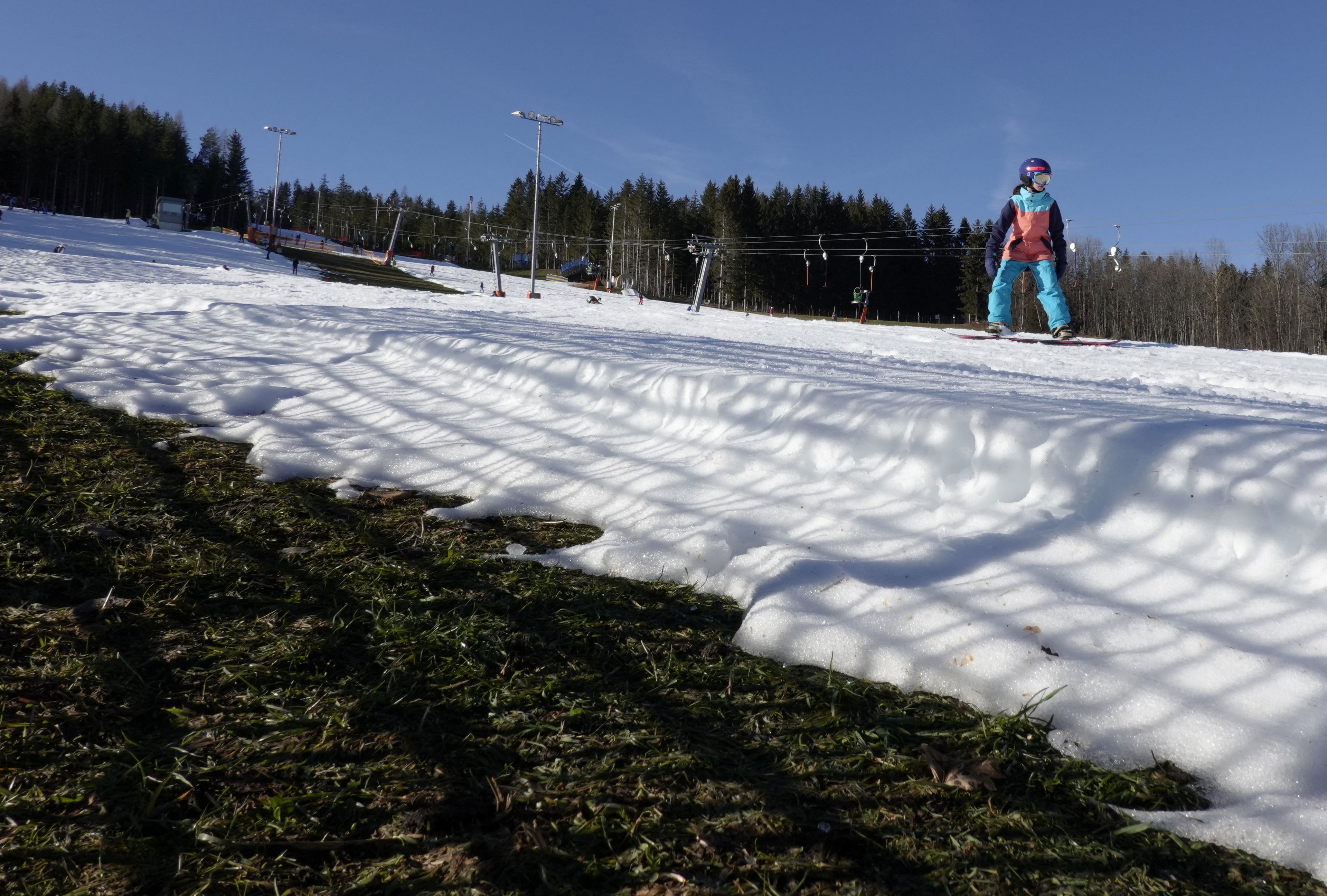 Una persona practica snowboard en una pista de esquí artificial en la estación de esquí de St. Corona, mientras unas temperaturas inusualmente cálidas azotan Austria.