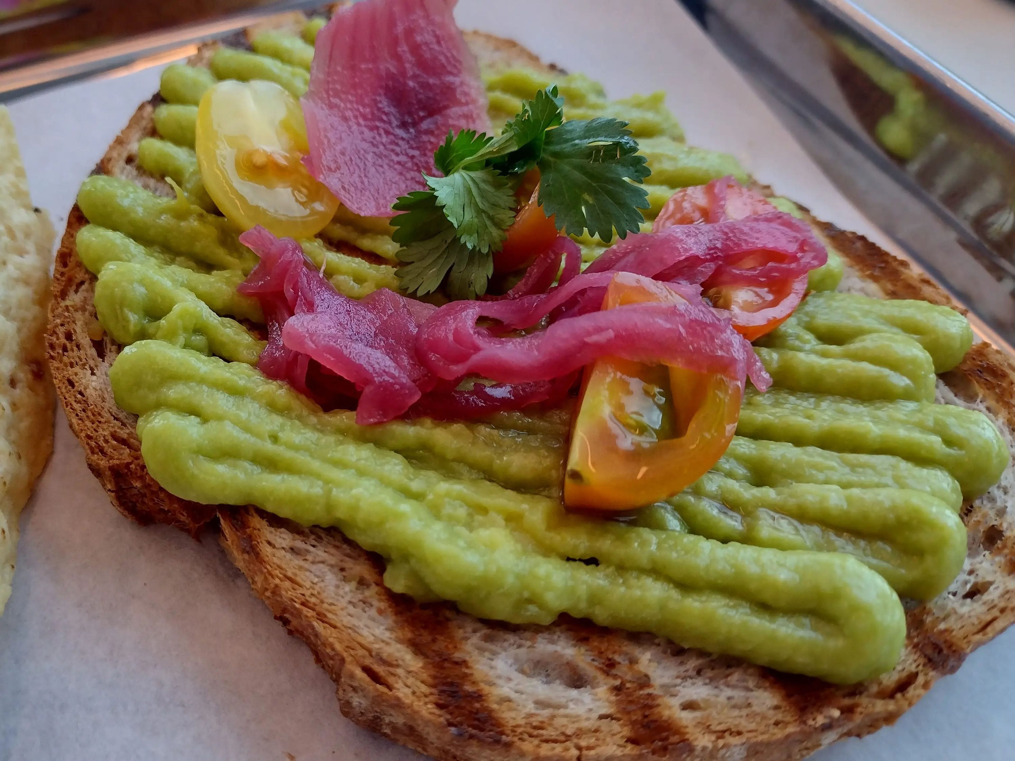 Plated avocado toast with pickled onions on top.