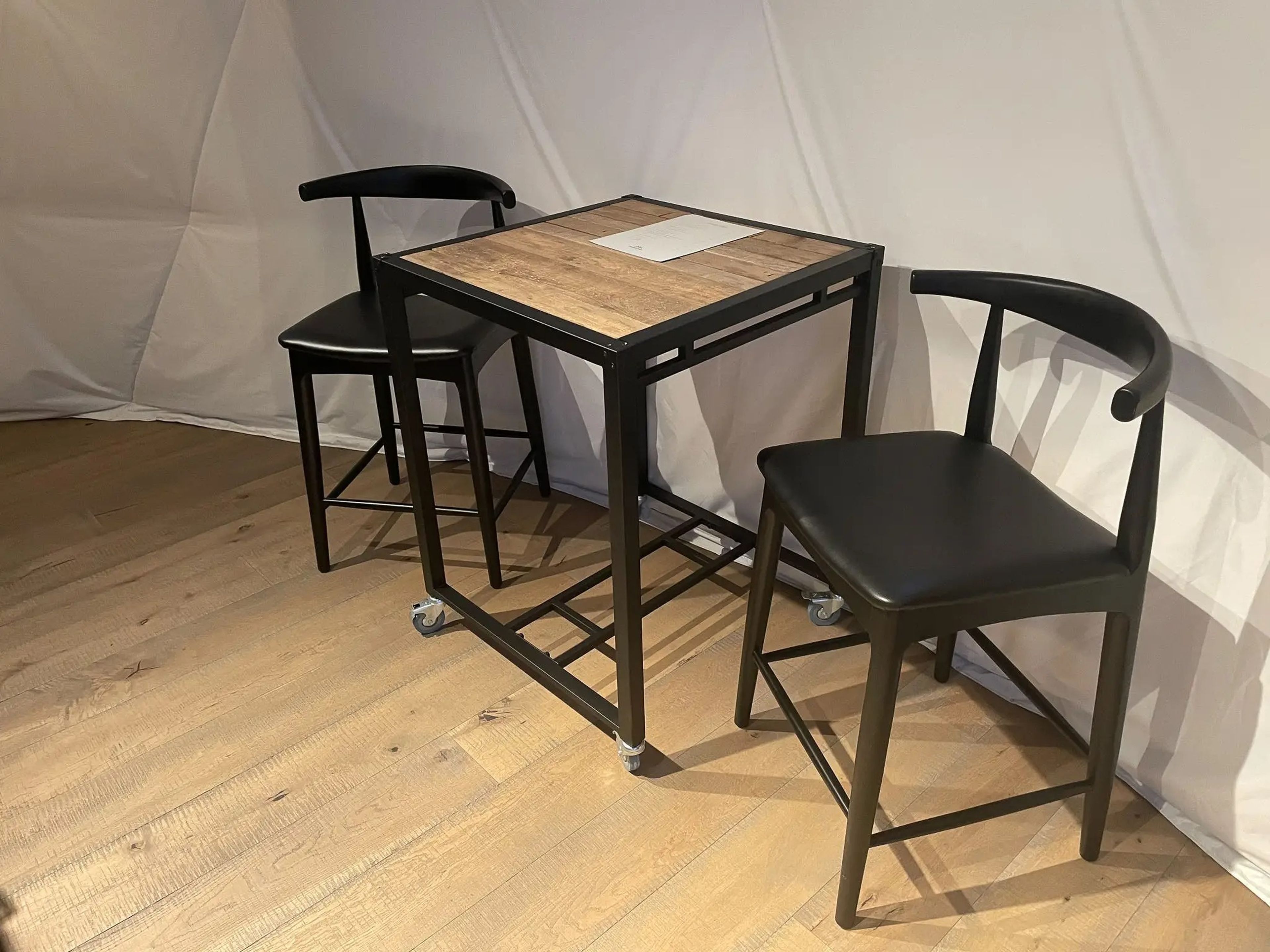 Una mesa pequeña con 2 sillas cerca de la cocina.
