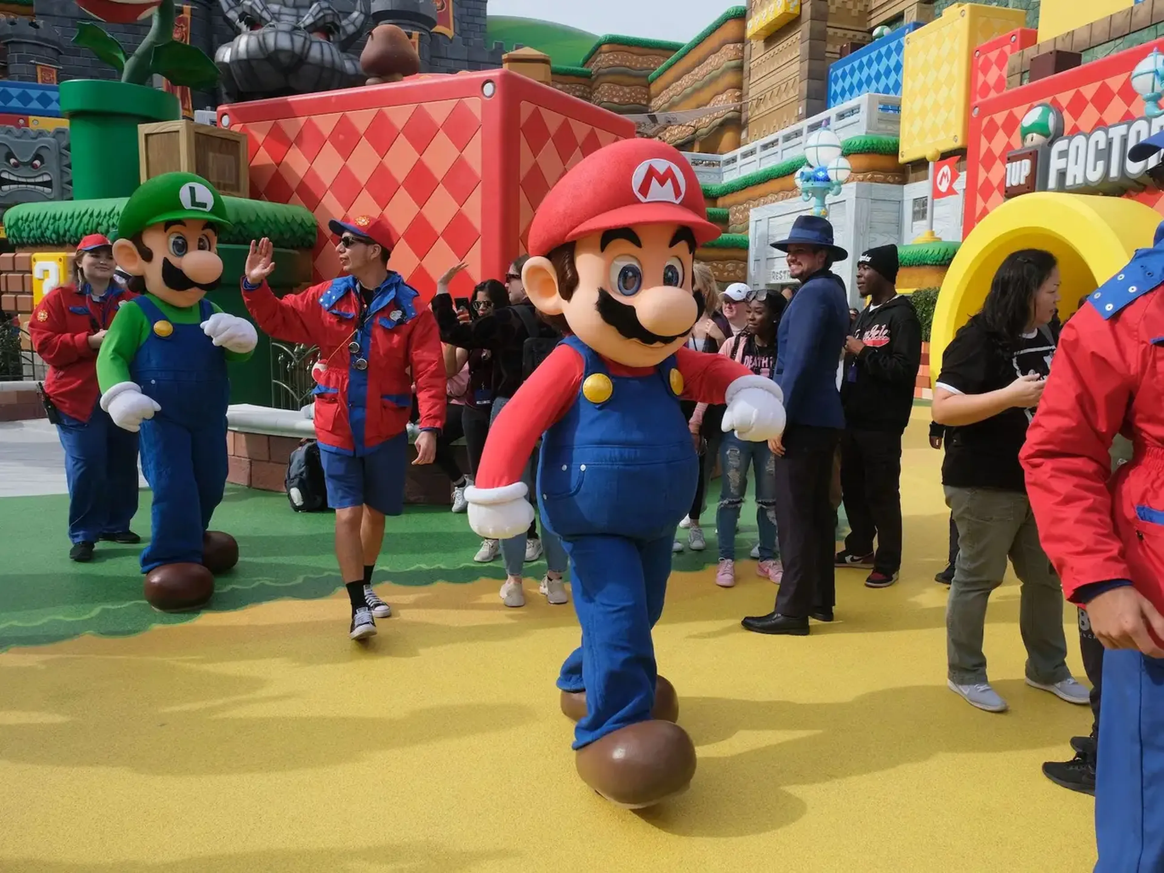 Mario y Luigi son escoltados entre la multitud en su camino a un descanso durante una vista previa de Super Nintendo World en Universal Studios en Los Ángeles, California, el 13 de enero de 2023.