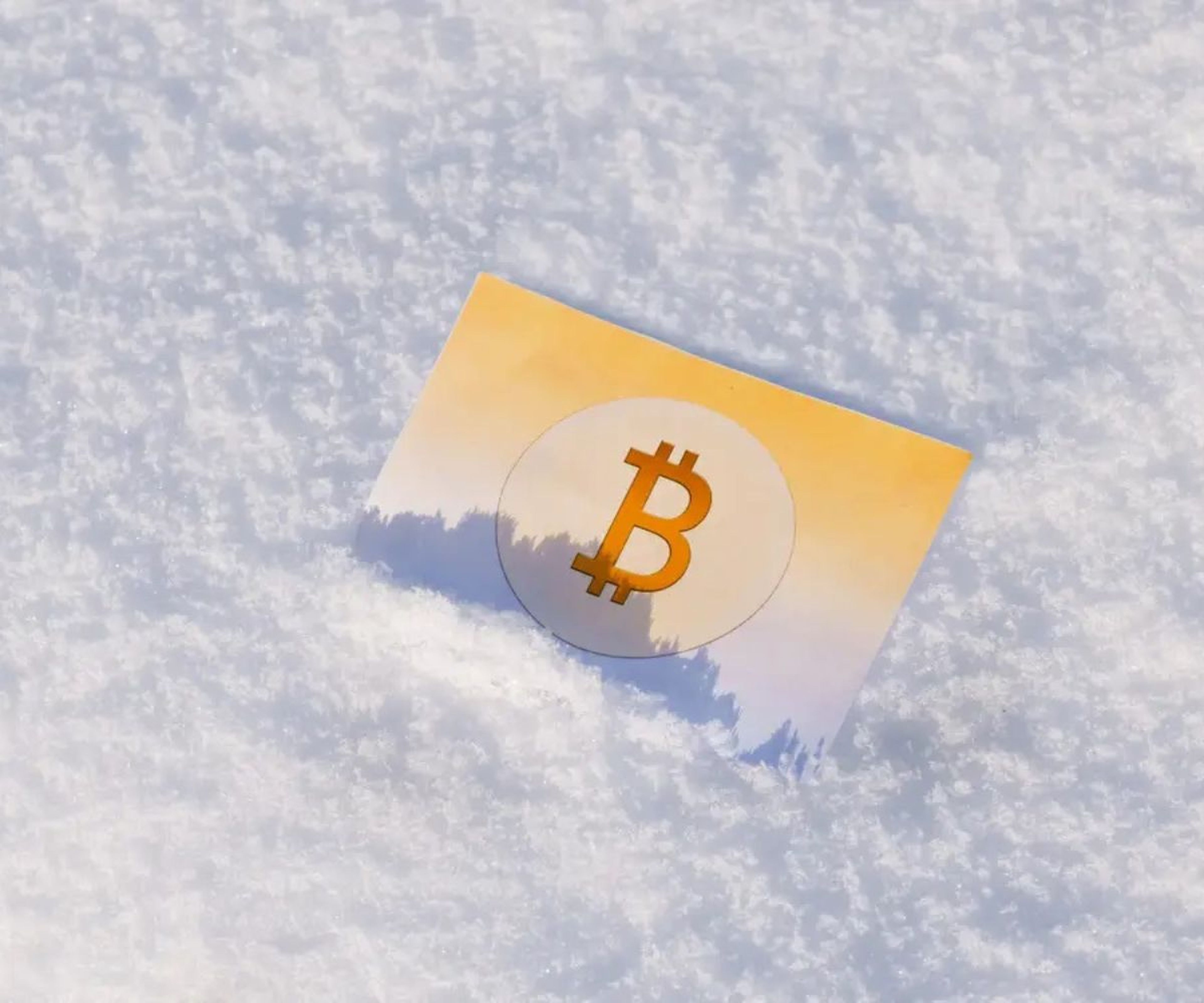 Una tarjeta con el símbolo de bitcoin en la nieve. 