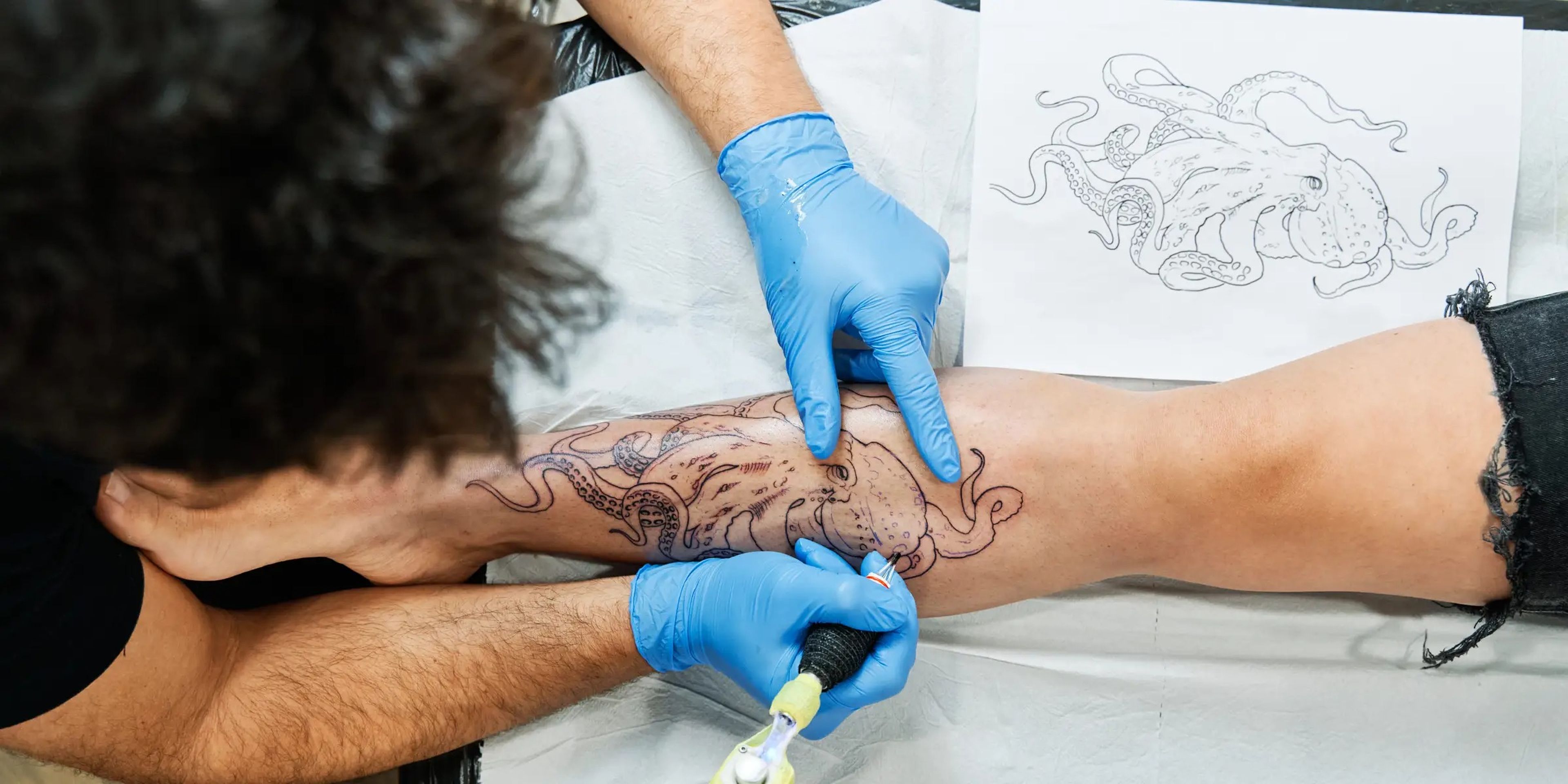 Tattoo artst inking octopus design on client's leg