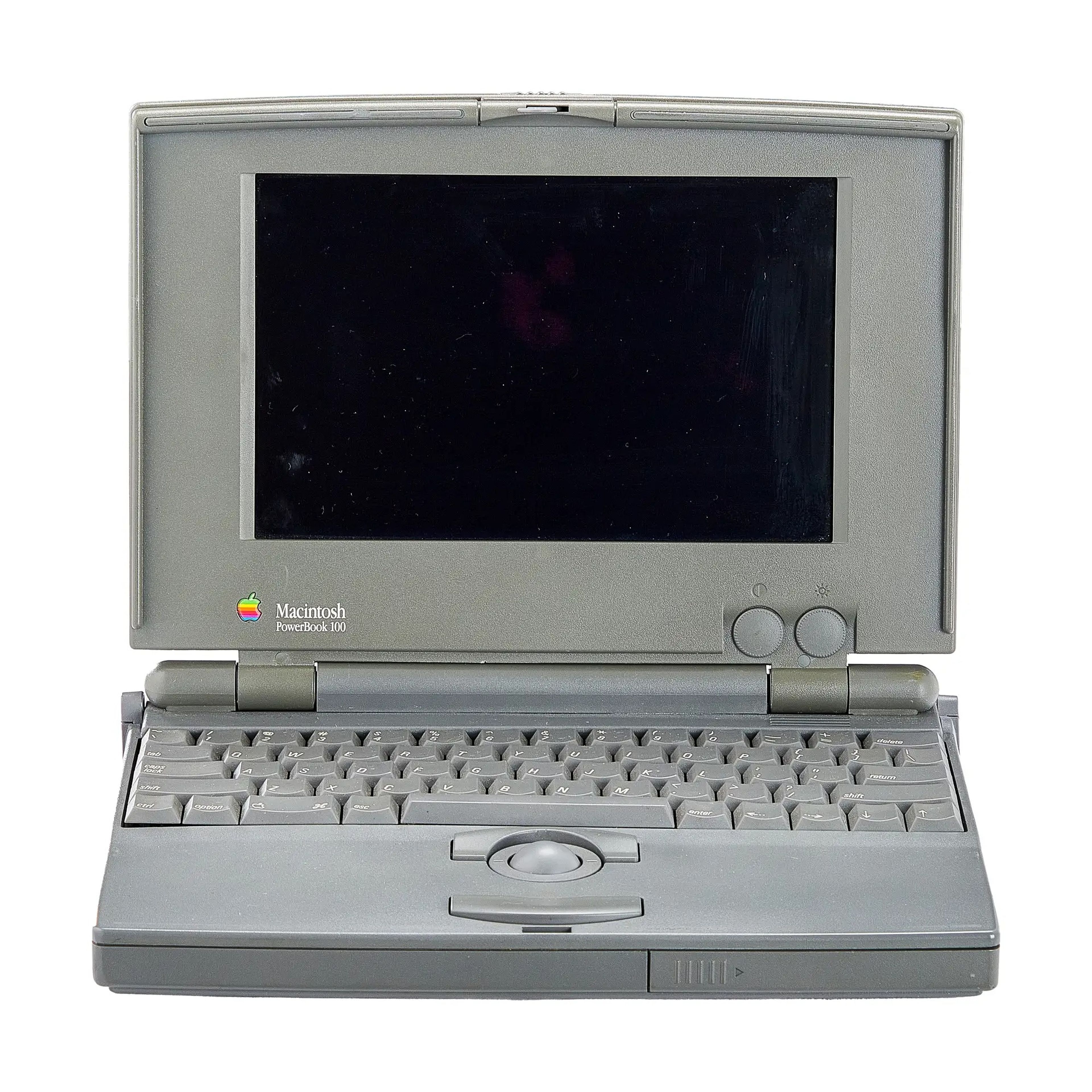 1991 PowerBook 100 that is grey with a black screen, a keyboard, and a roller ball mouse