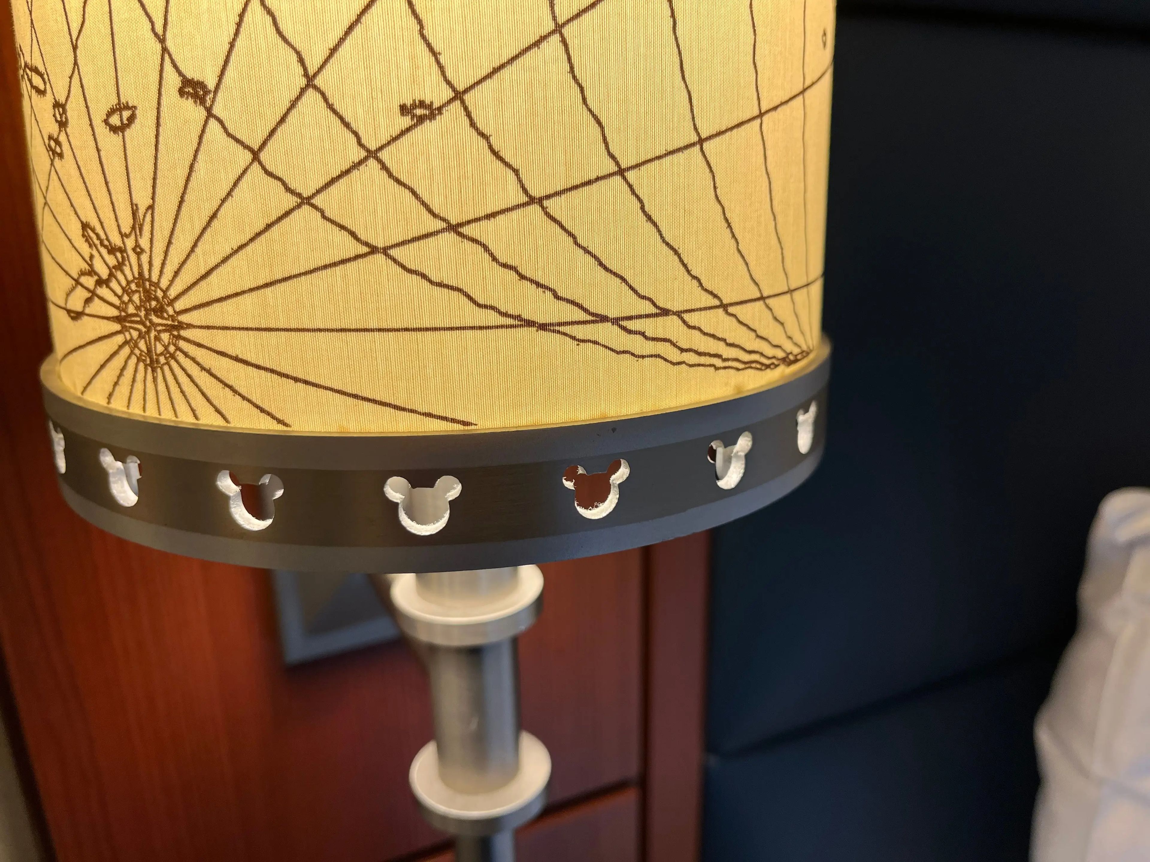 closeup view of a map-themed lamp with mickey mouse details in a family stateroom on a disney cruise