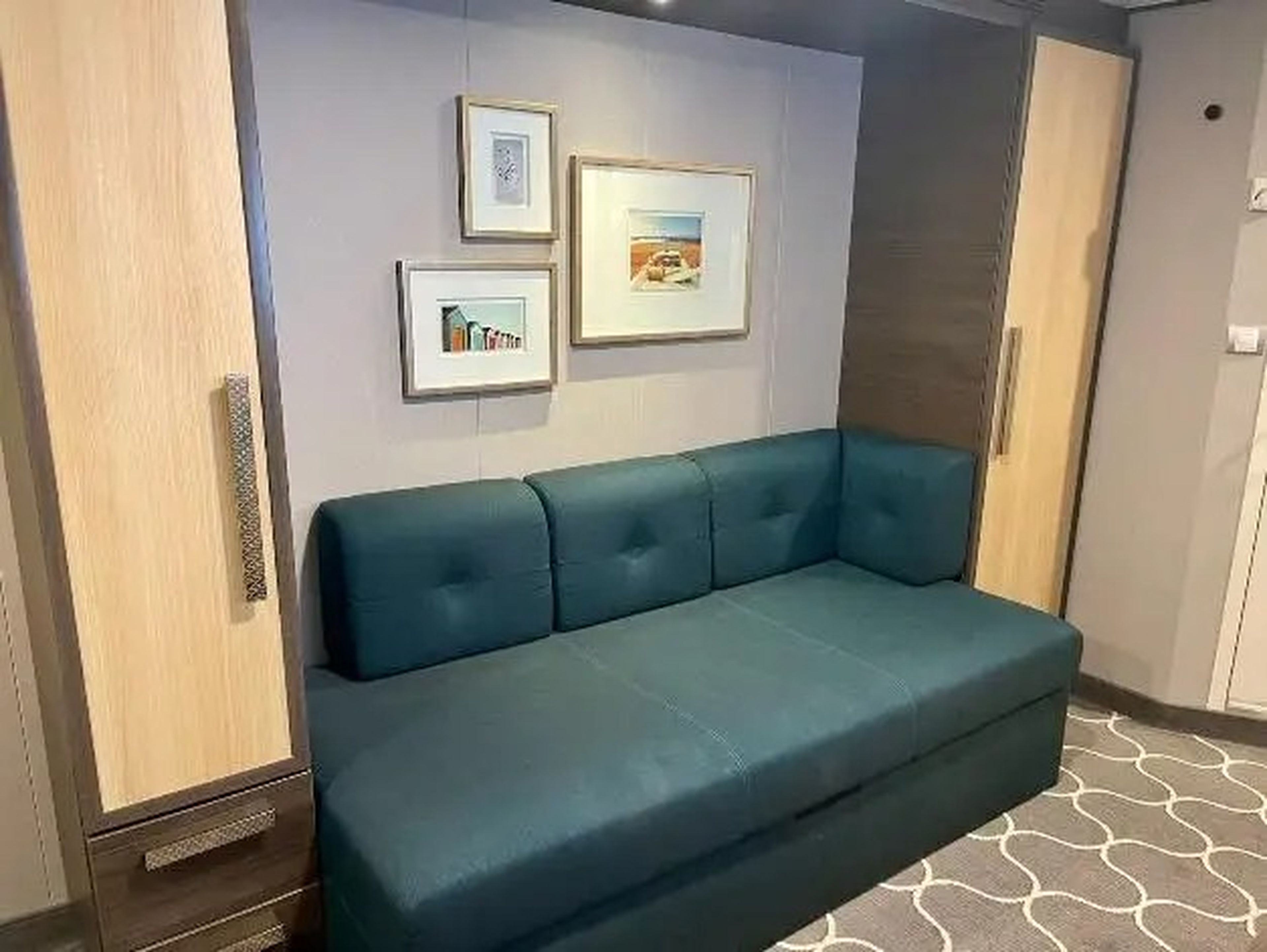 couch in symphony of the seas room with photos hanging on the wall above it