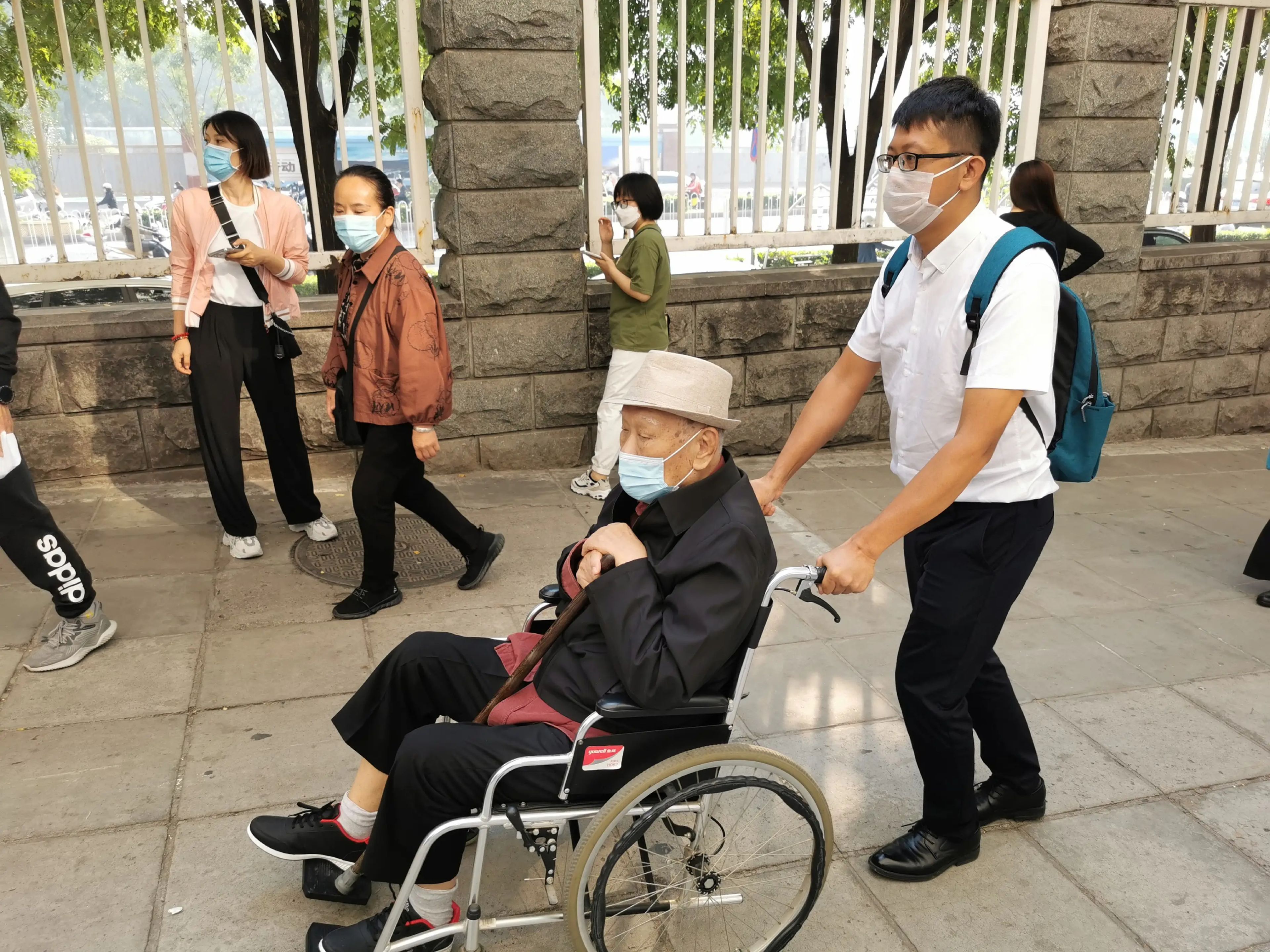 Un cuidador o "enfermero asistencial", acompaña a una persona de 92 años que vive en su propia casa a un hospital de Pekín.