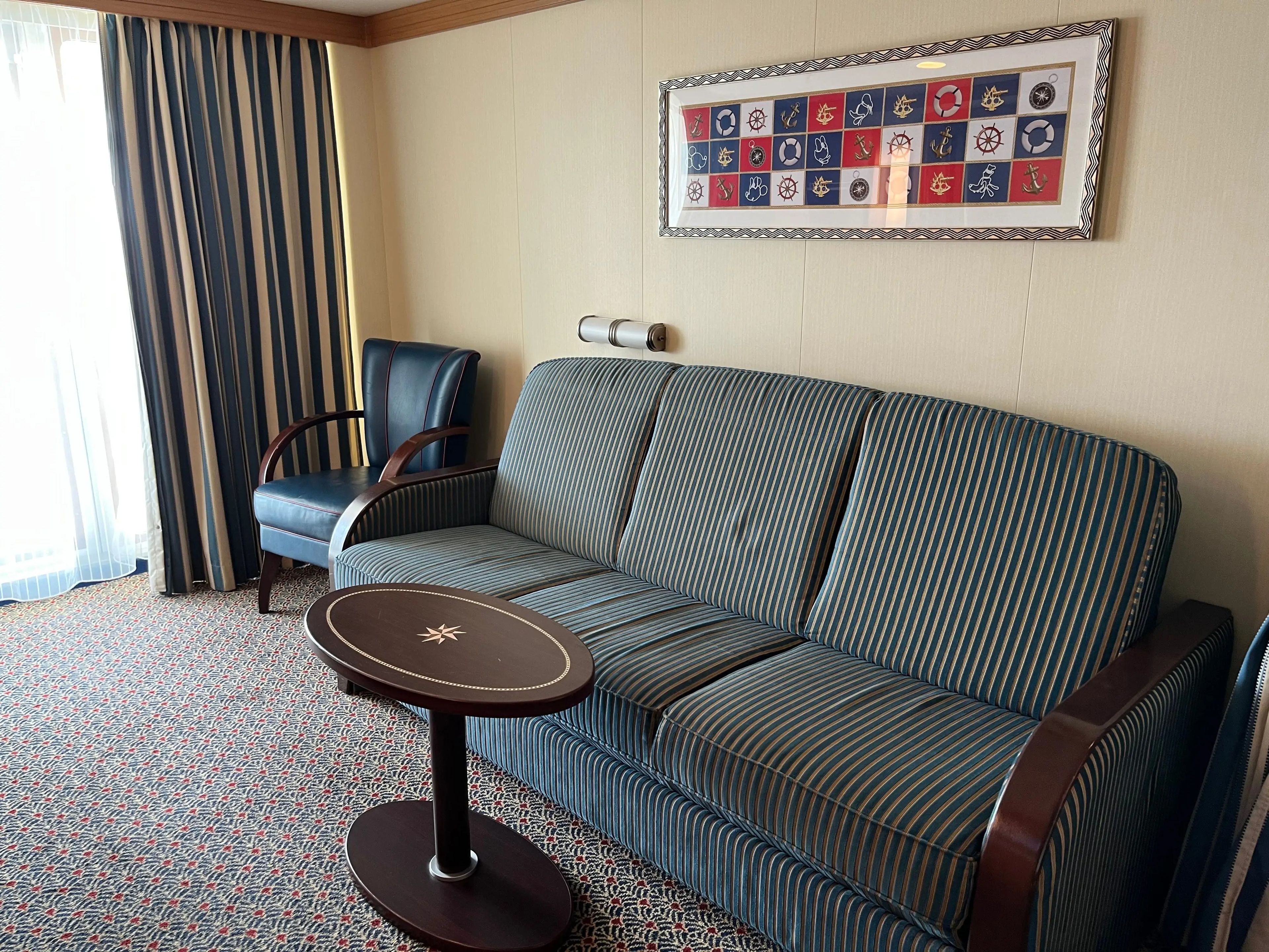 living area with a couch and a chair in a family stateroom on a disney cruise