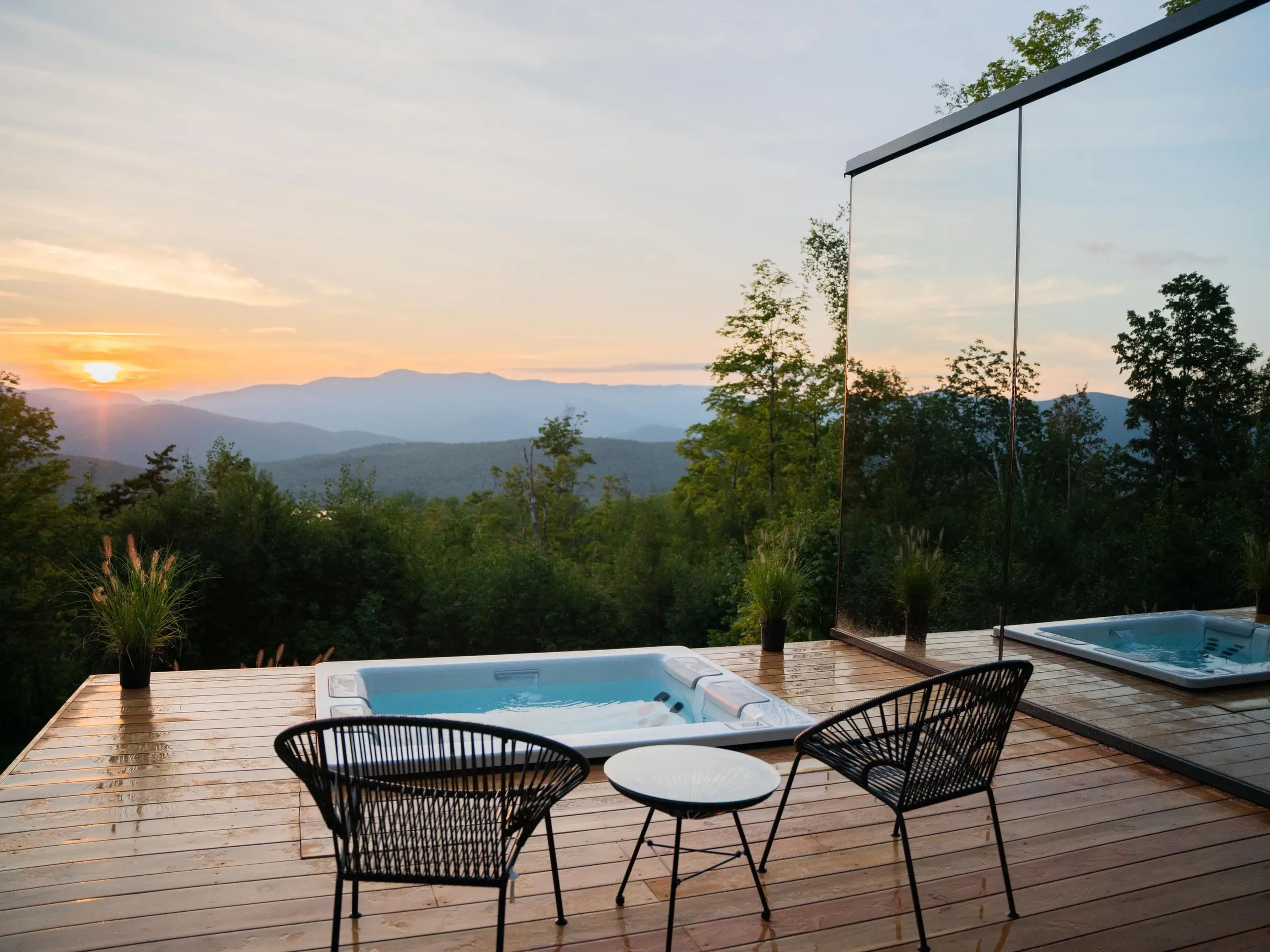 Photo of lawn chairs and a hot tub overlooking mountains at sunset