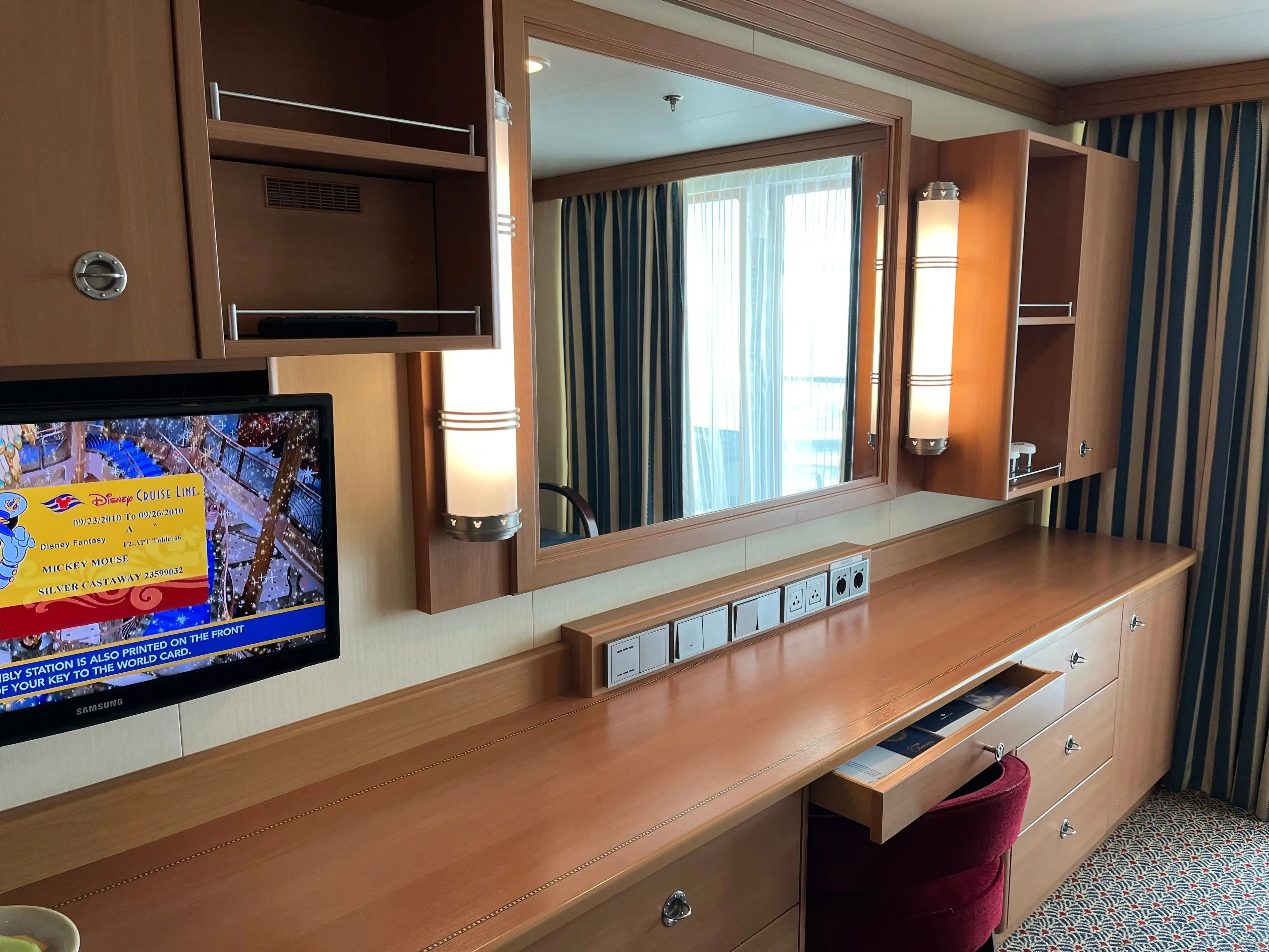 tv and storage area in the living room of a family stateroom on a disney cruise