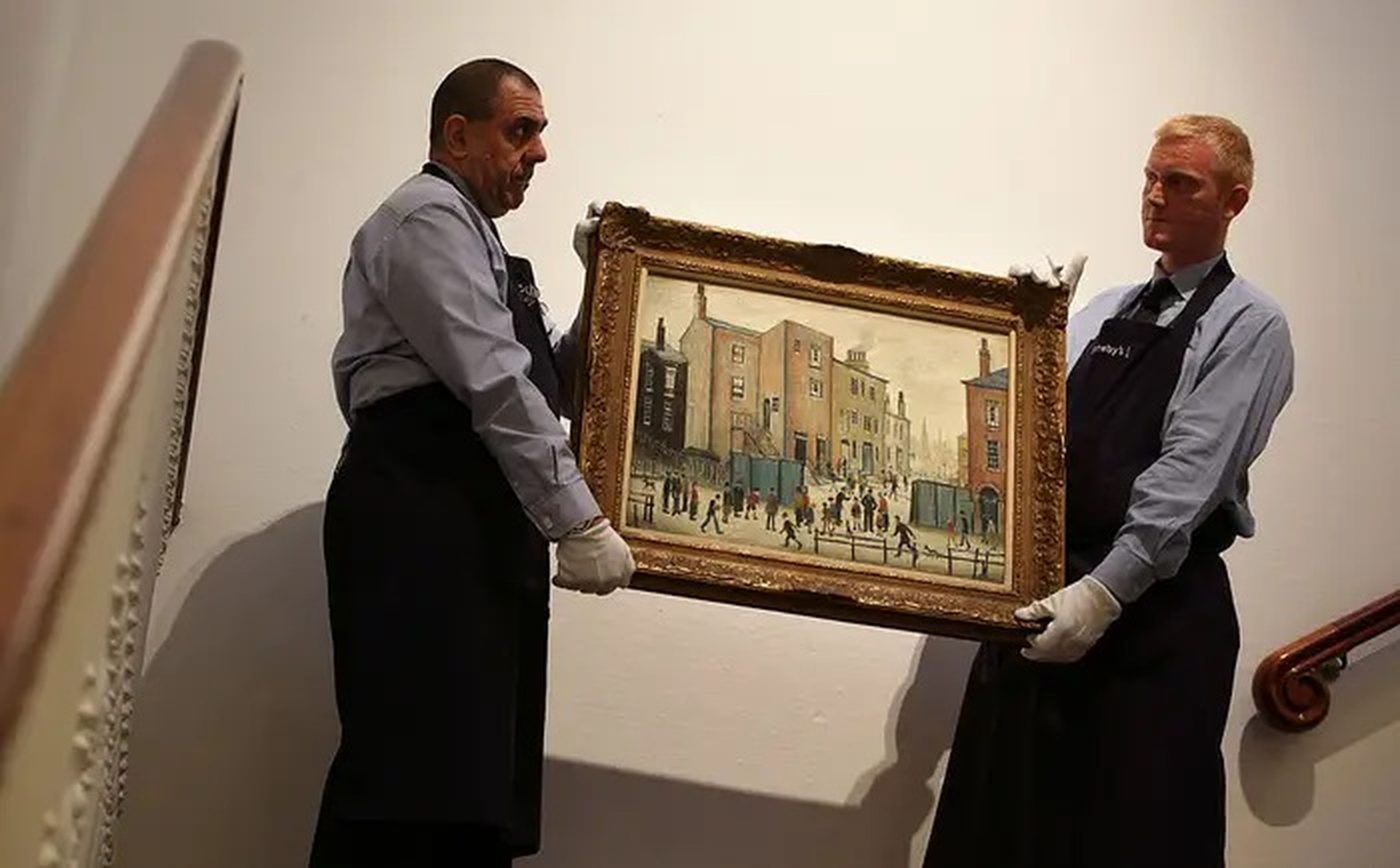 2 trabajadores de la casa de subastas de Sotheby's mueven una pintura de L.S. Lowry el 24 de septiembre de 2009 en Londres, Inglaterra.