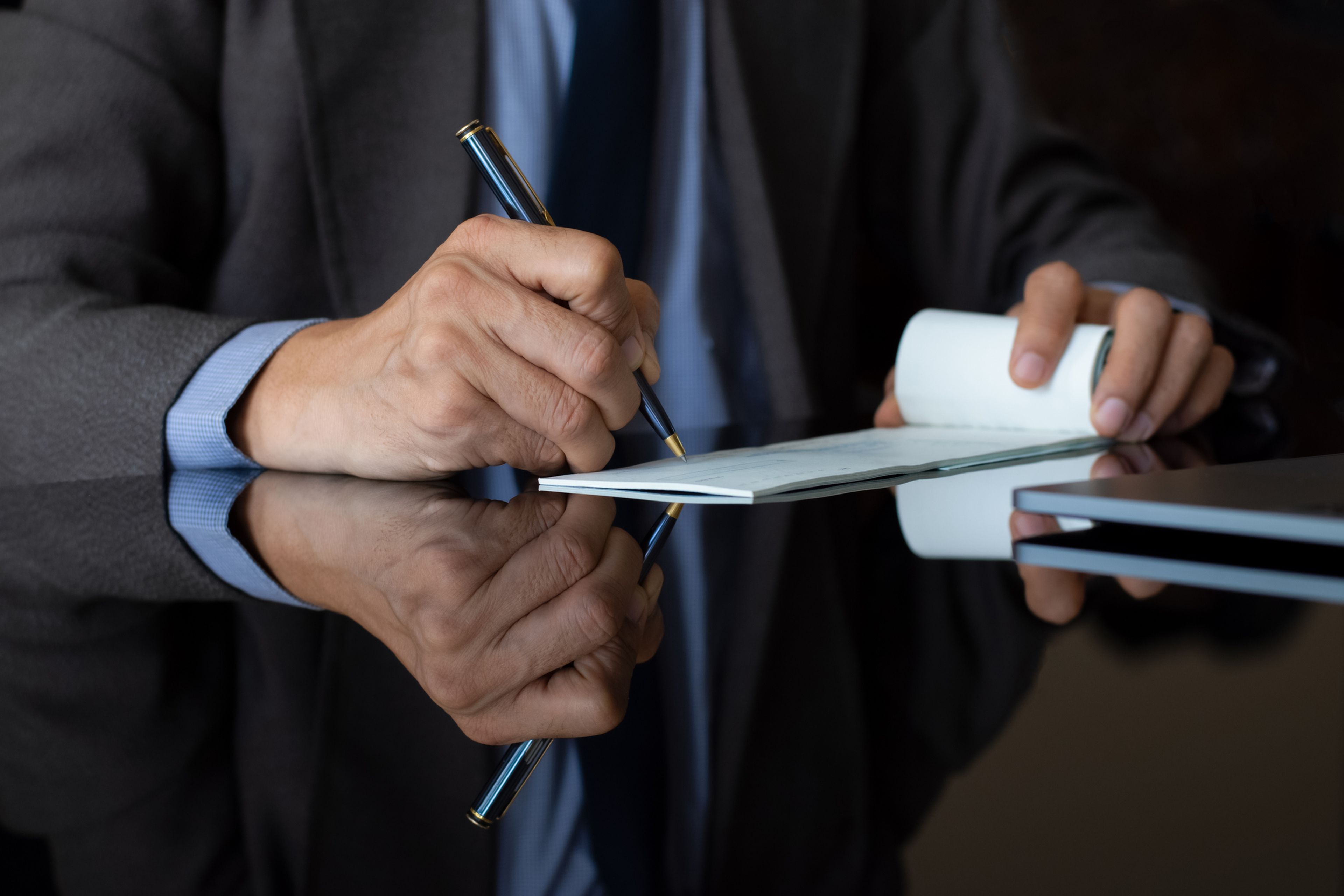 Un hombre escribe o firma en un cheque