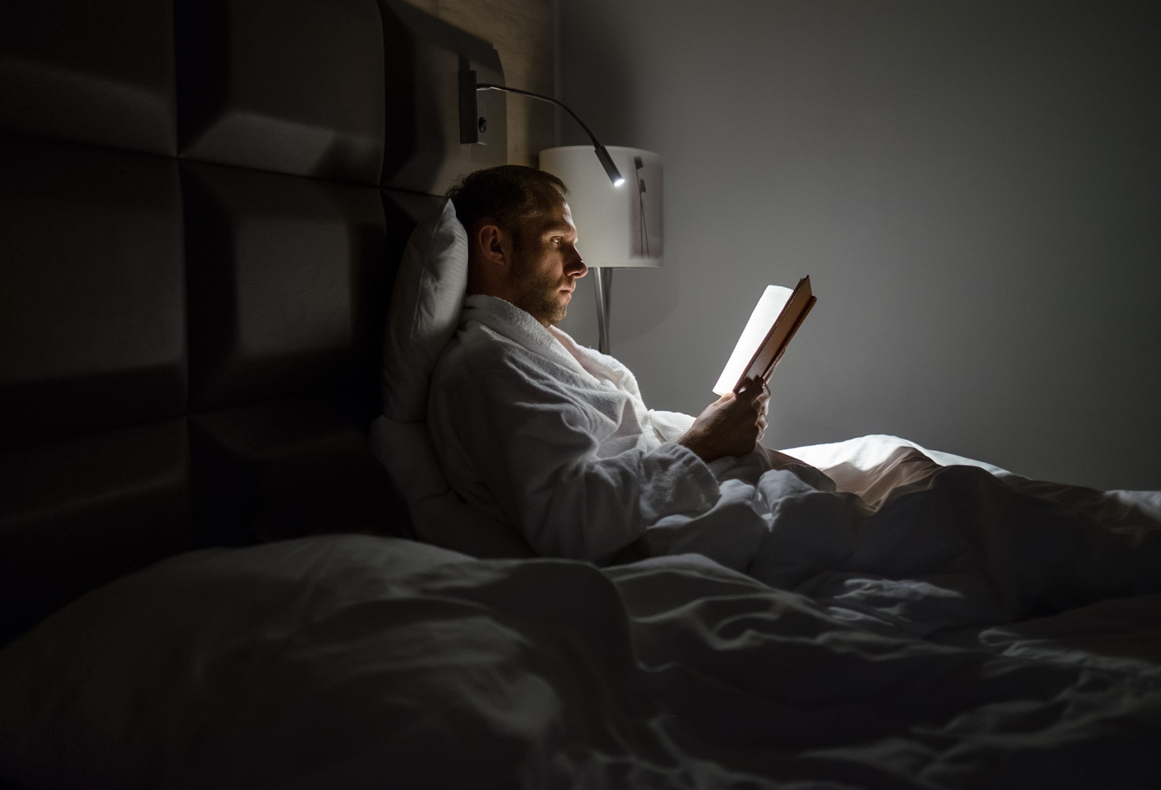 Un hombre lee en la cama.