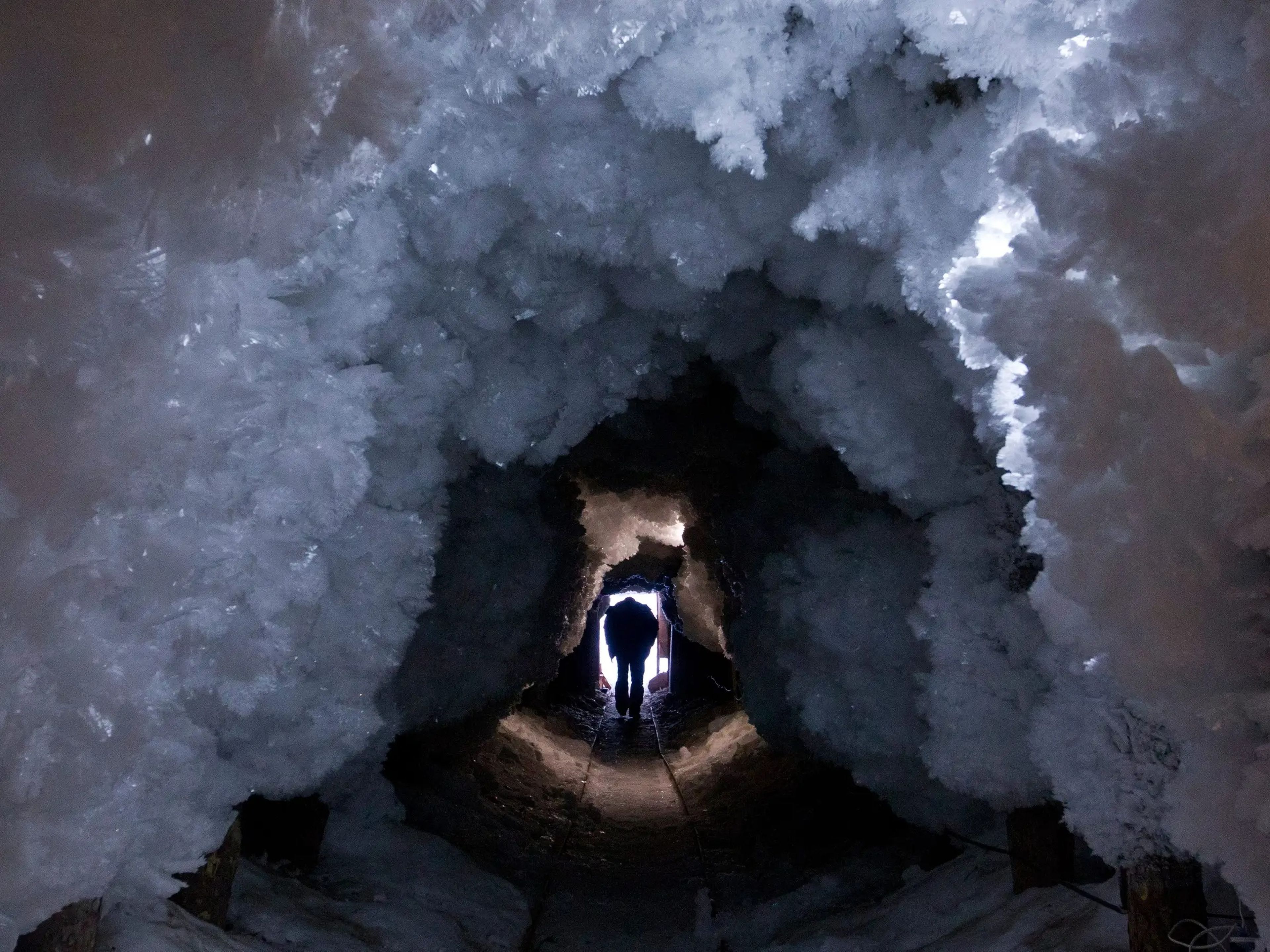 A man walks through a tunnel formed from crystals of permafrost outside the village of Tomtor.
