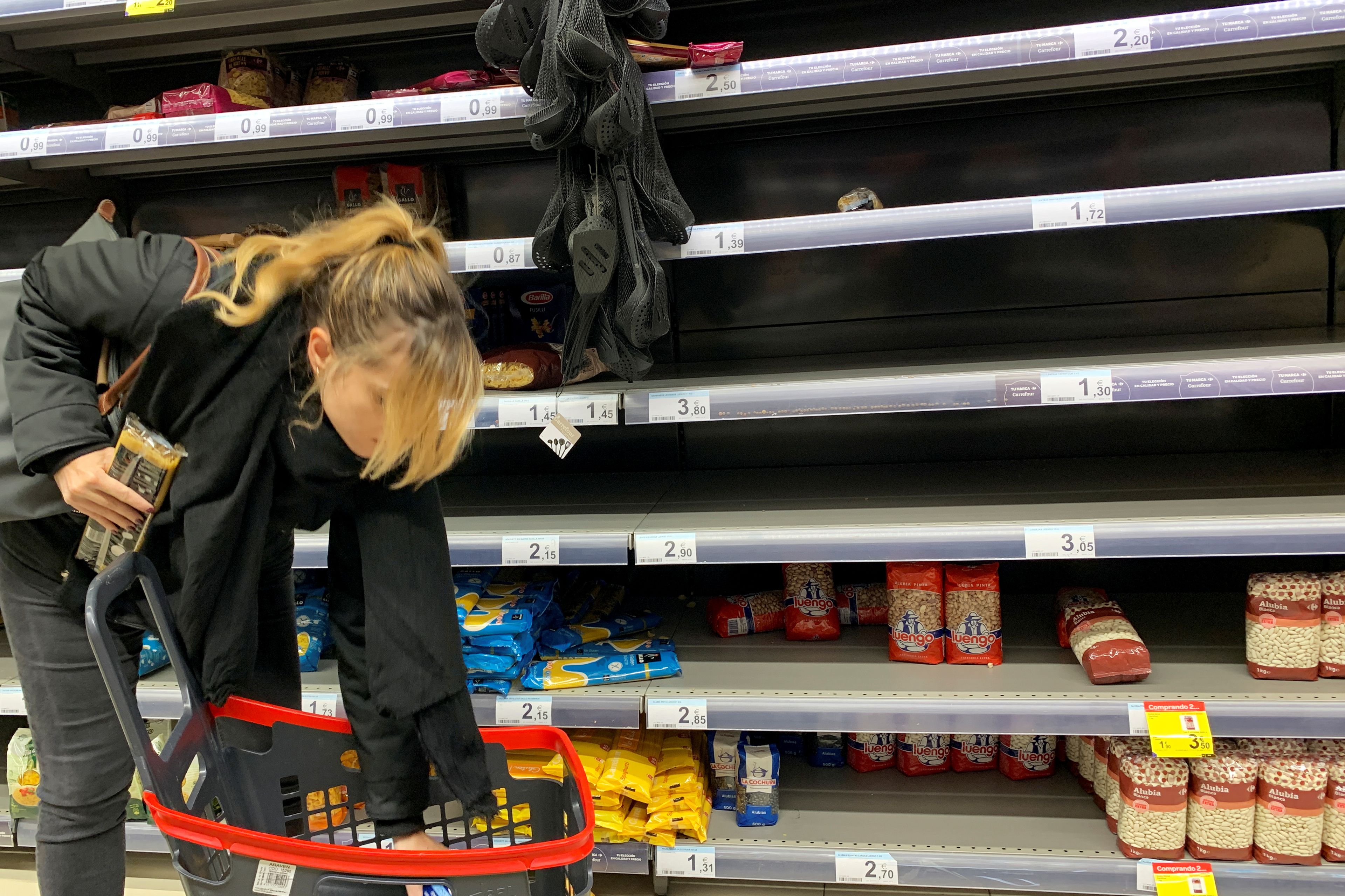 Mujer joven hace la compra en un supermercado medio vacío (2020)