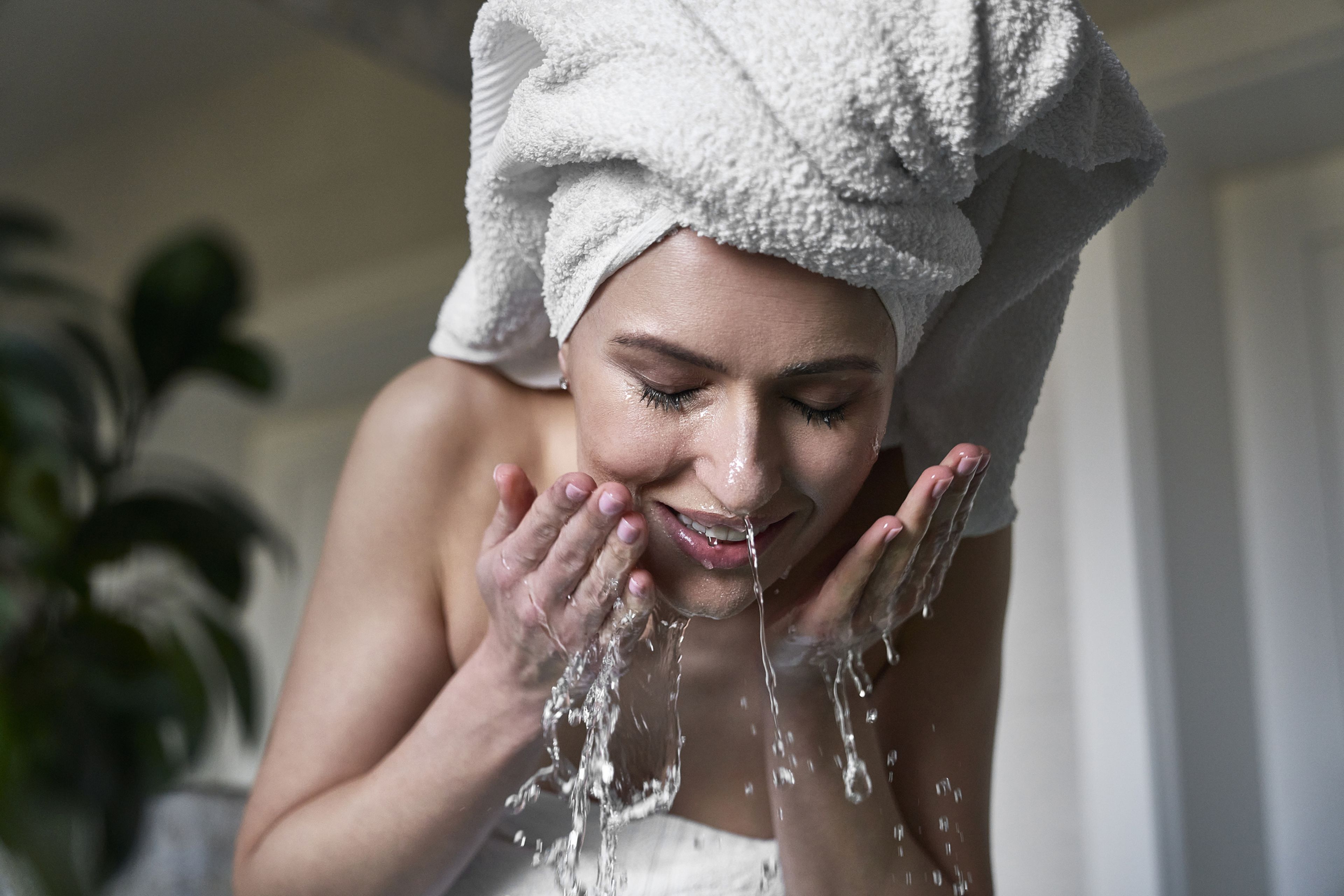 Mujer lavándose la cara con agua