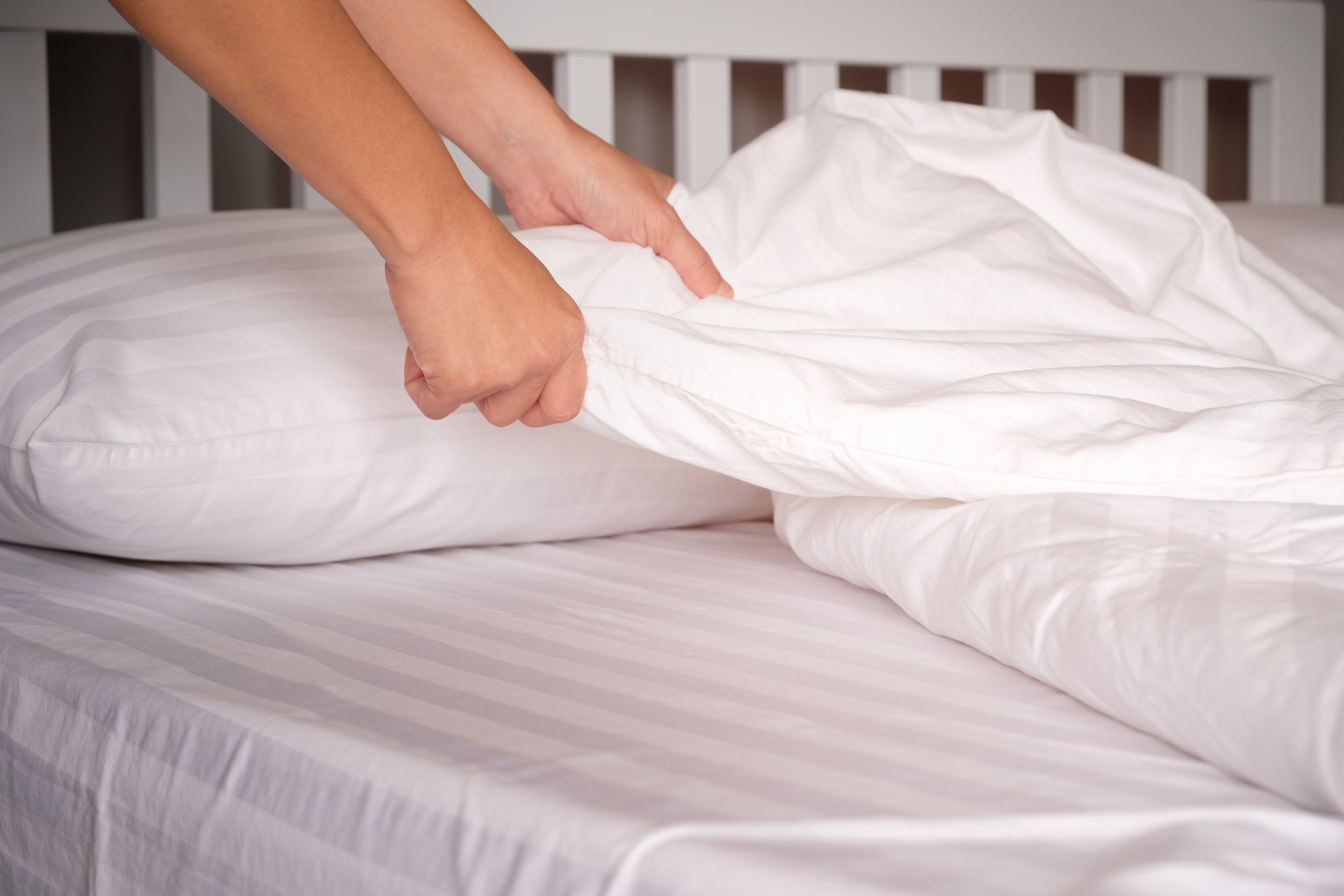 Persona poniendo las sábanas sobre la cama