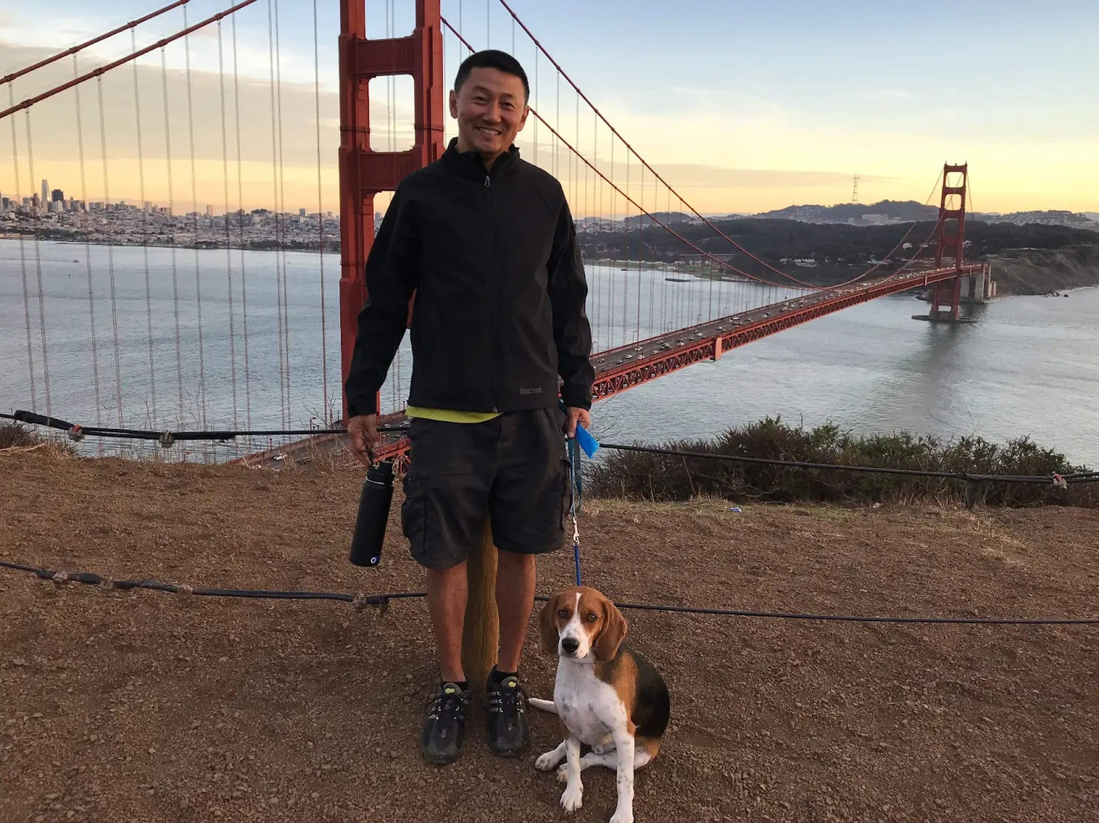 Richard Sim and his dog Auggie posing in front of the iconic Golden Gate bridge.