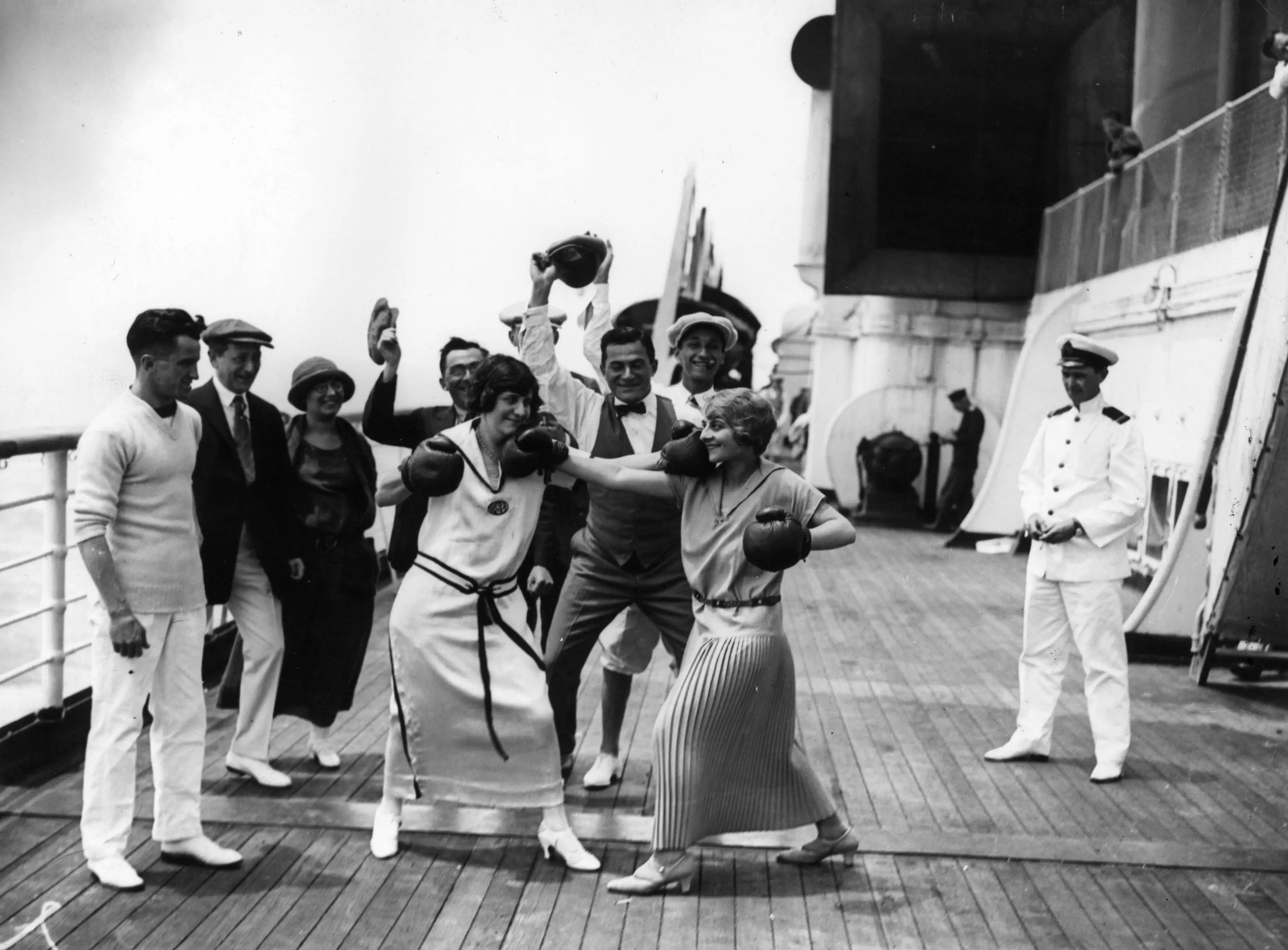 Pasajeras boxeando a bordo del transatlántico Berengaria de Cunard, observadas por otros pasajeros y un oficial, hacia julio de 1923.