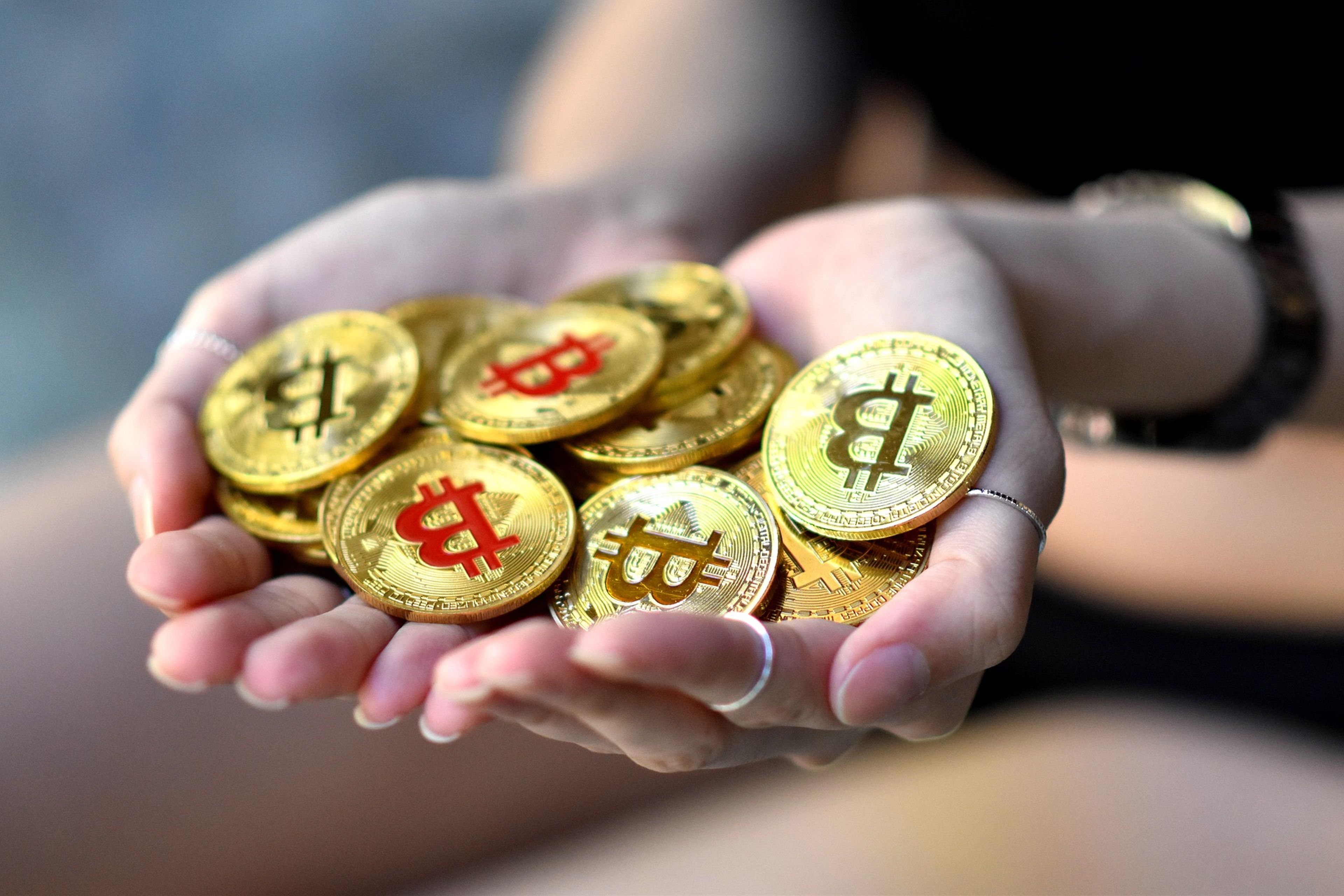 Unas manos sujetan varias monedas de bitcoin. 