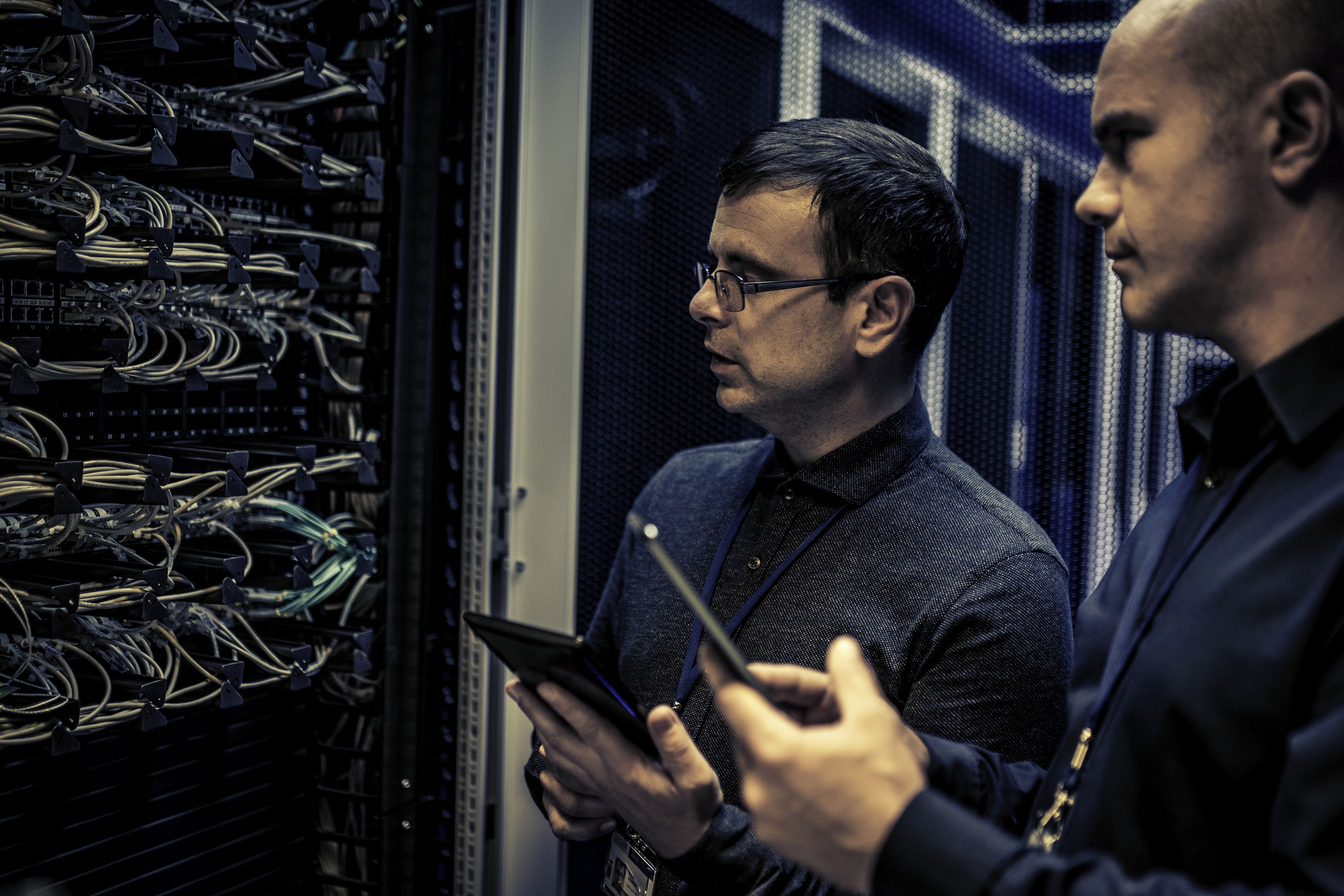 2 técnicos analizan las conexiones de un servidor.