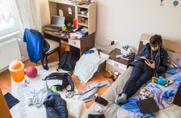 Adolescente en la cama, en una habitación desordenada