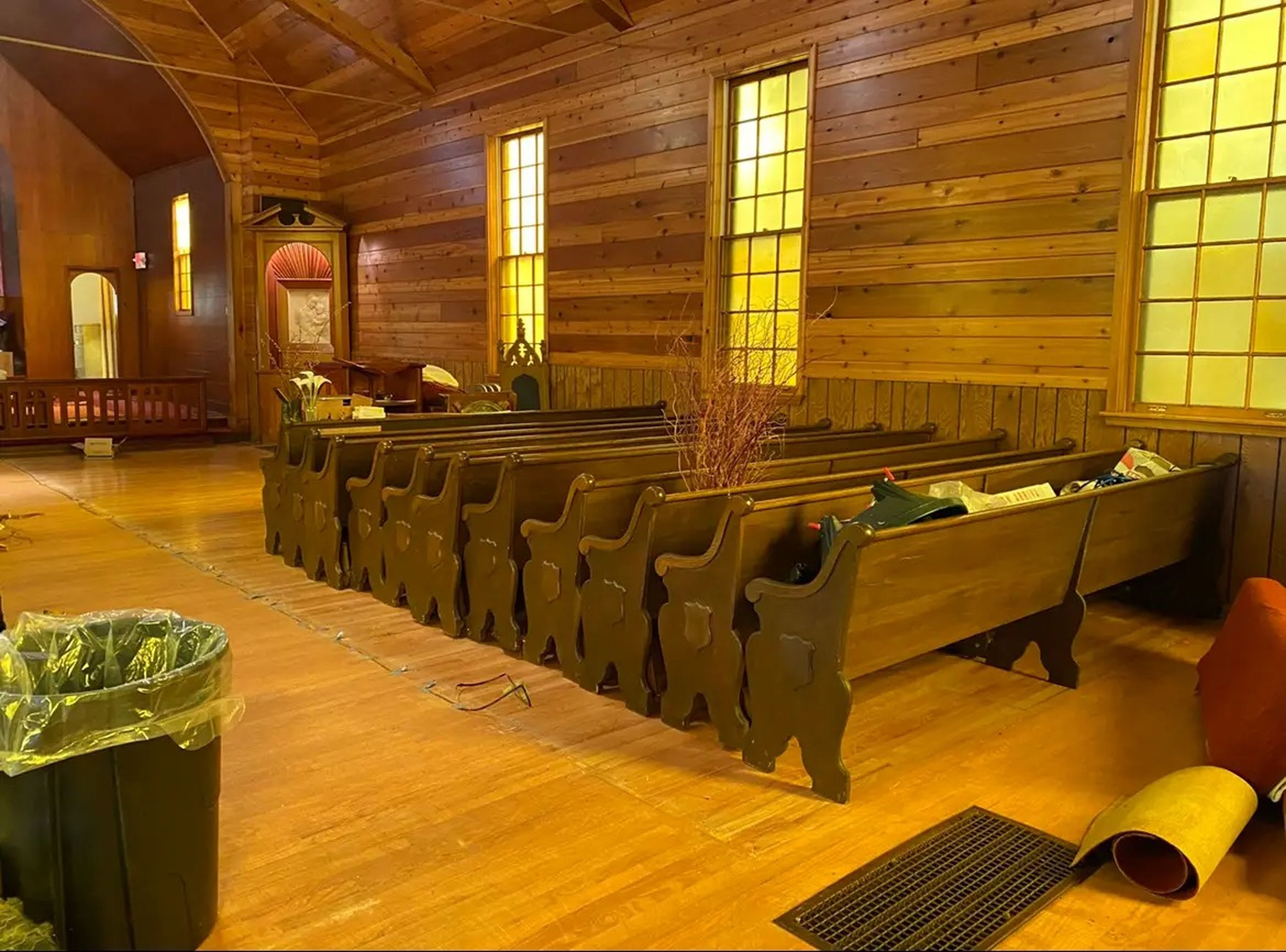 A church nave with wood-clad walls and wood pews.