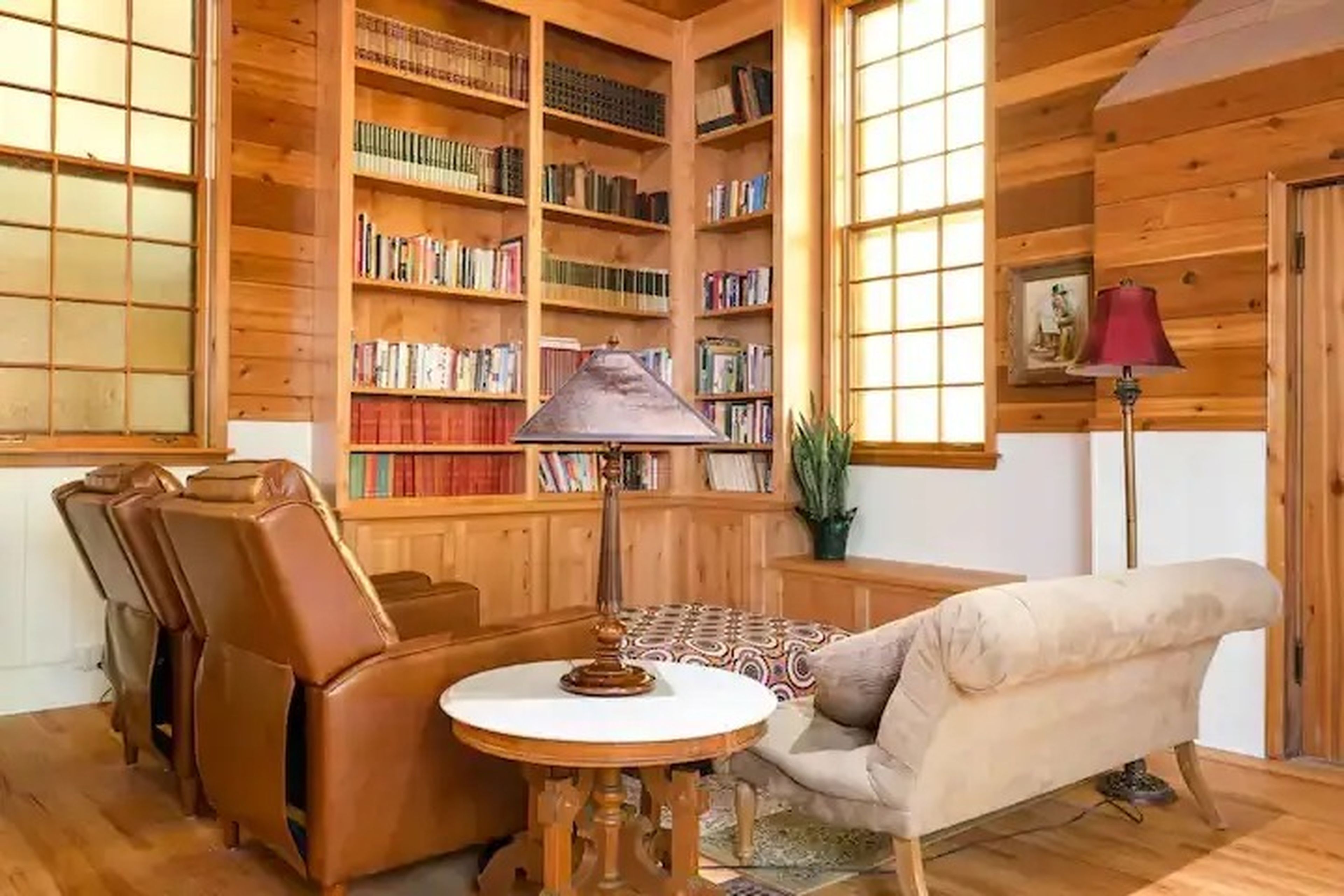 A corner of a room with high ceilings, built-in bookshelves, and seating.