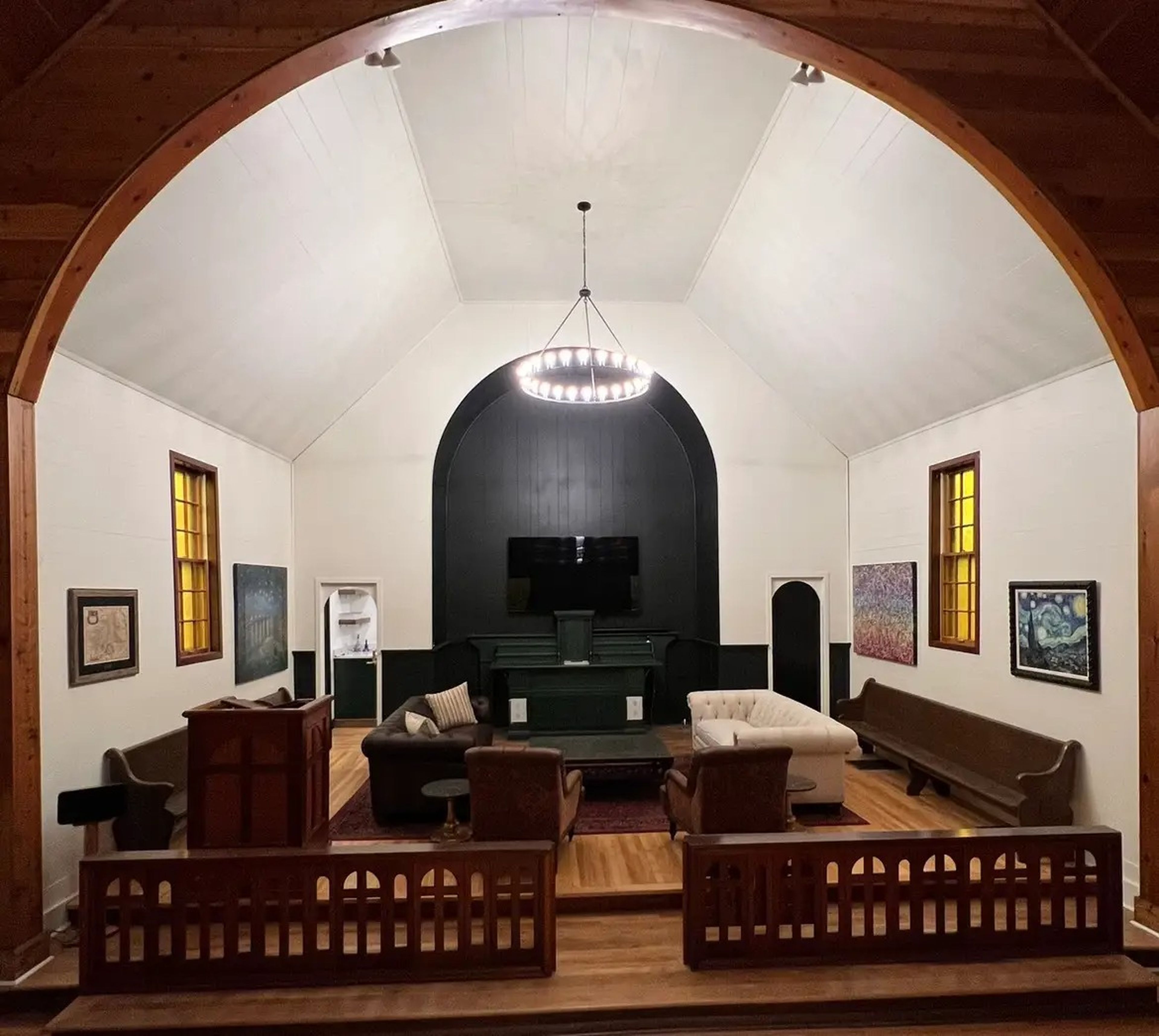 The former apse of a church has been turned into a living room with white walls.
