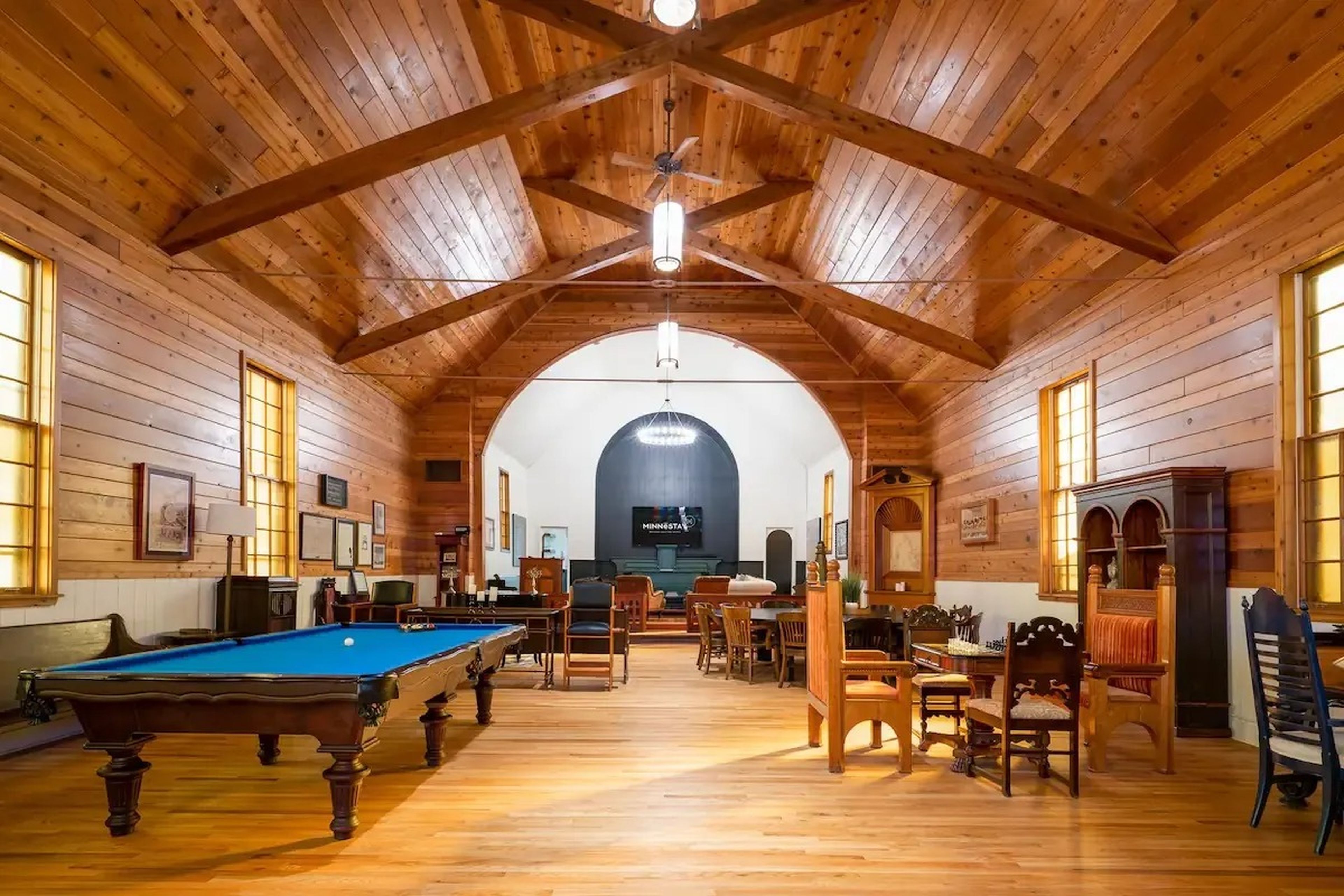 A former church nave decorated as a living space with a pool table and various seating areas.