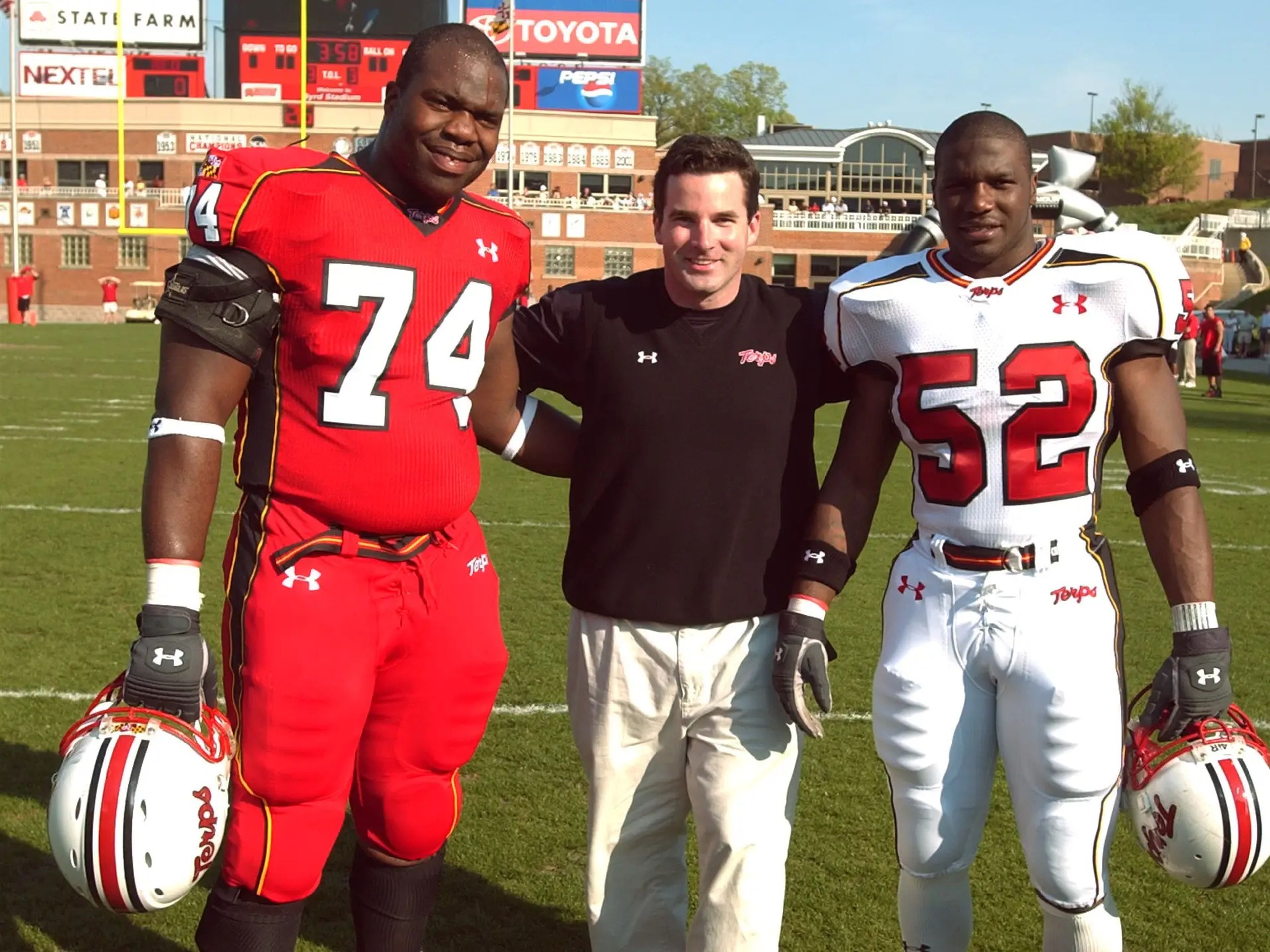 Plank en 2004 posando con jugadores de fútbol de la Universidad de Maryland, donde fue capitán de equipos especiales.