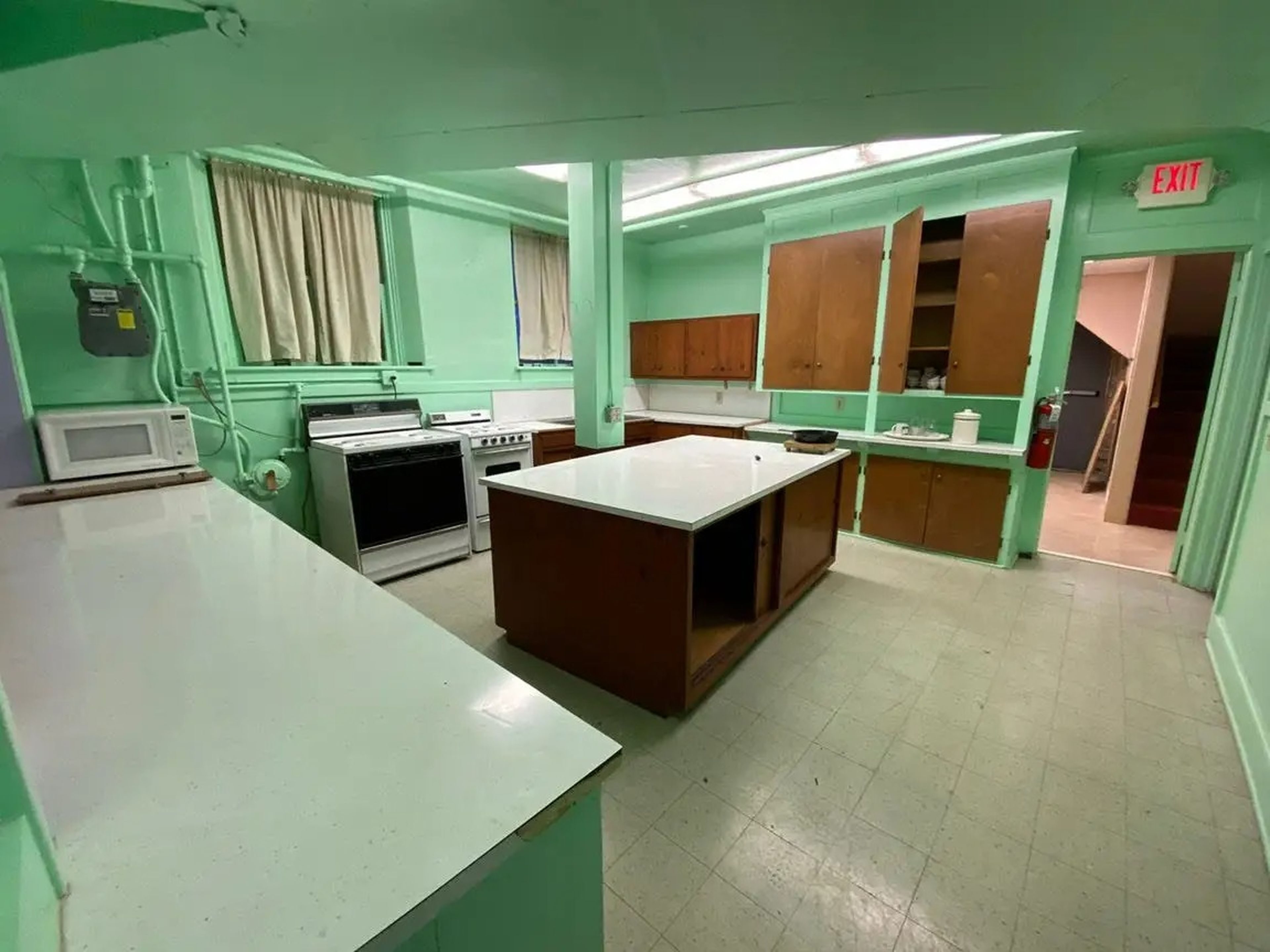 A kitchen with bright green walls, white floors, and fluorescent lighting.