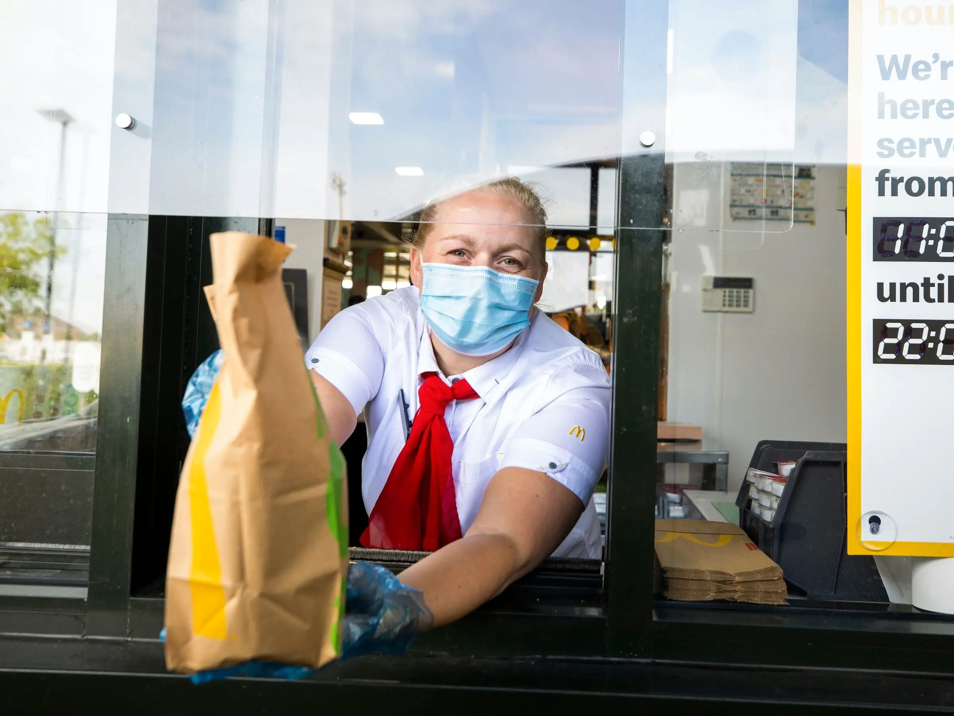 Un empleado de McDonald's entregando a un cliente su bolsa de comida.