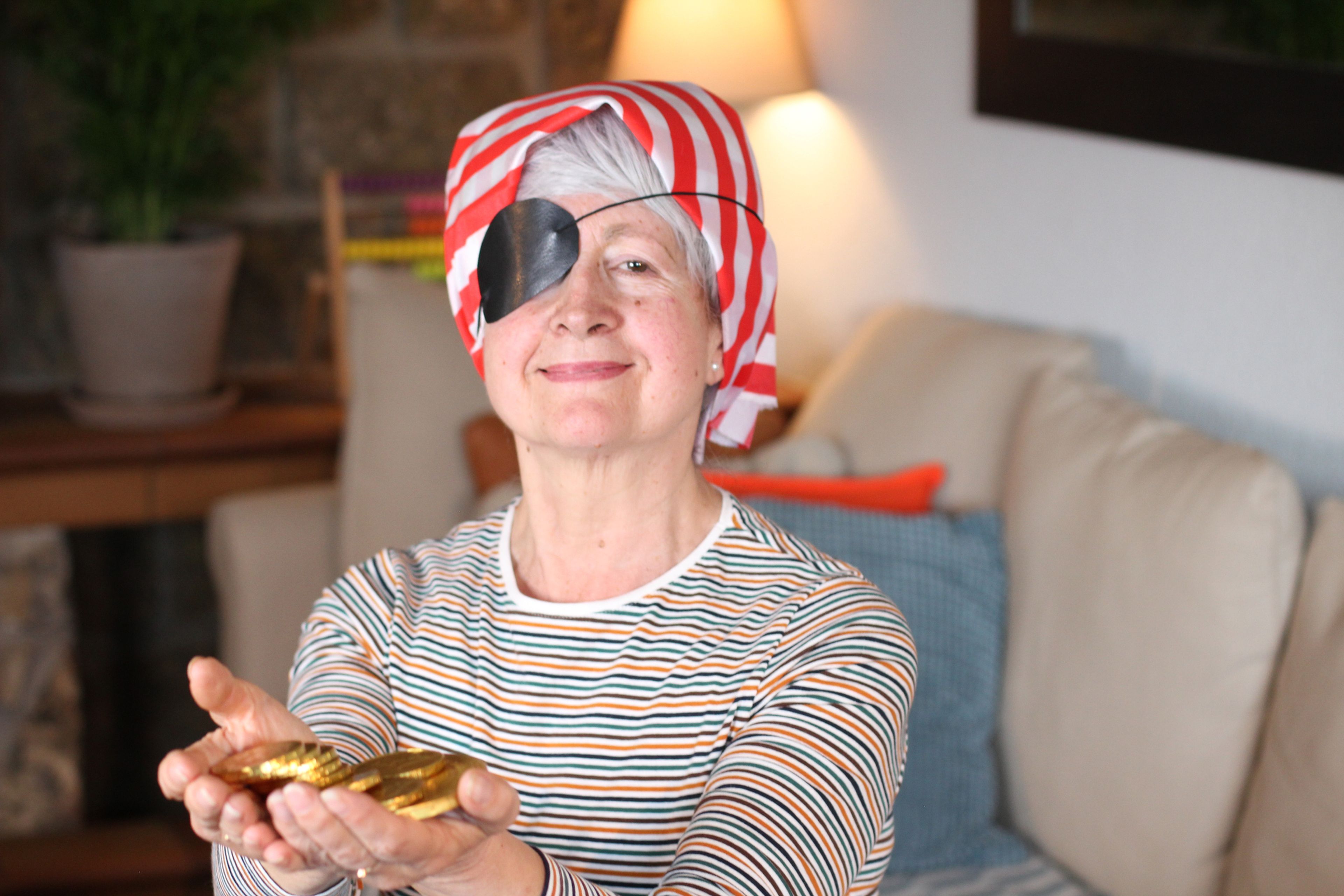 Una mujer con parche de pirata sujeta unas monedas de oro.