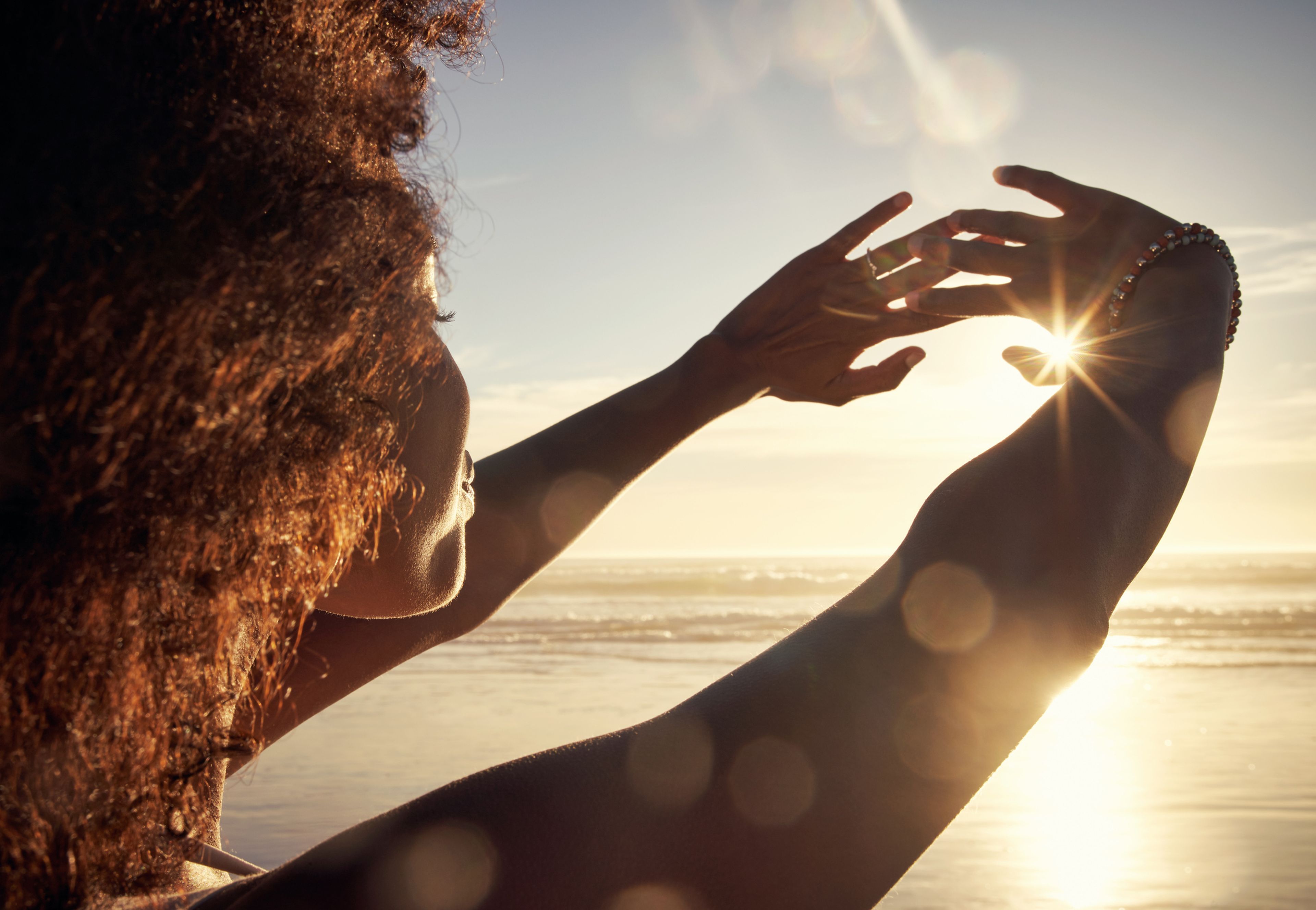 Una mujer tapa el sol con sus manos.