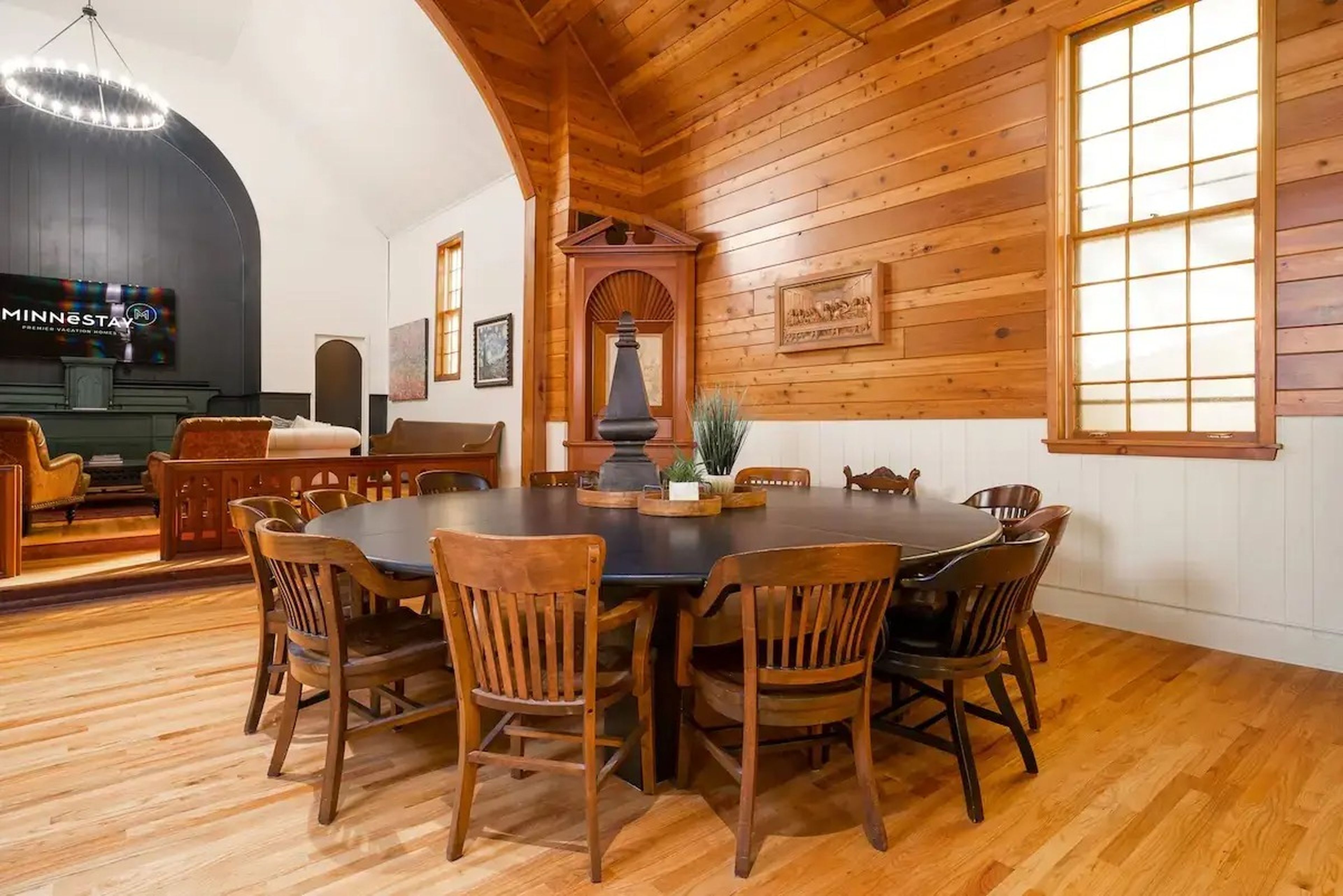 A room with wood walls and a large round table surrounded by many chairs.