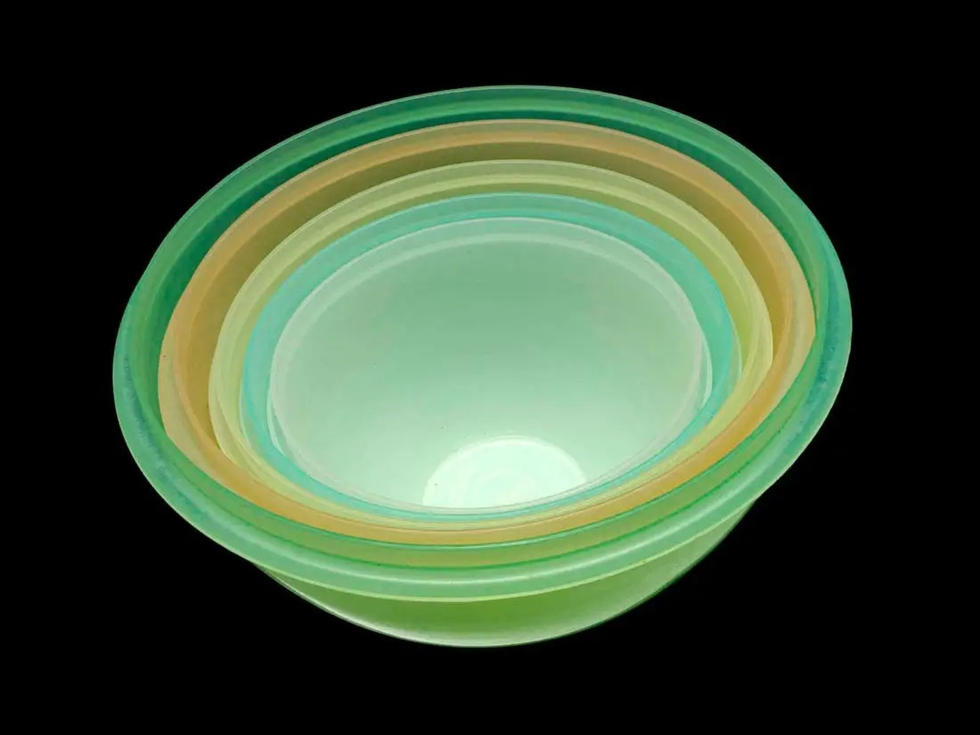 A set of Wonderlier Tupperware, four bowls in multiple sizes and colors, against a black background.