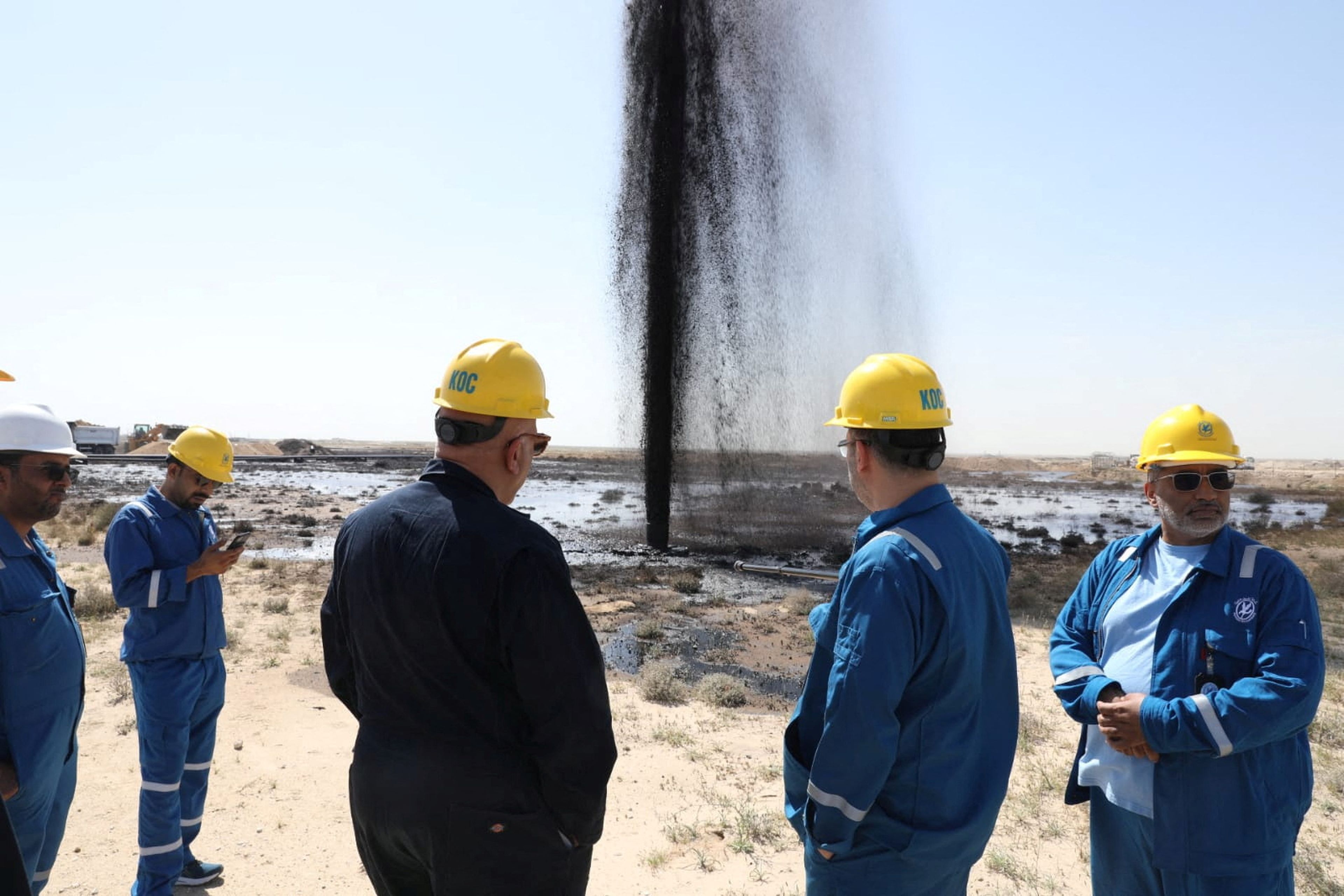 Trabajadores de Kuwait Oil Company observan un derrame de petróleo.