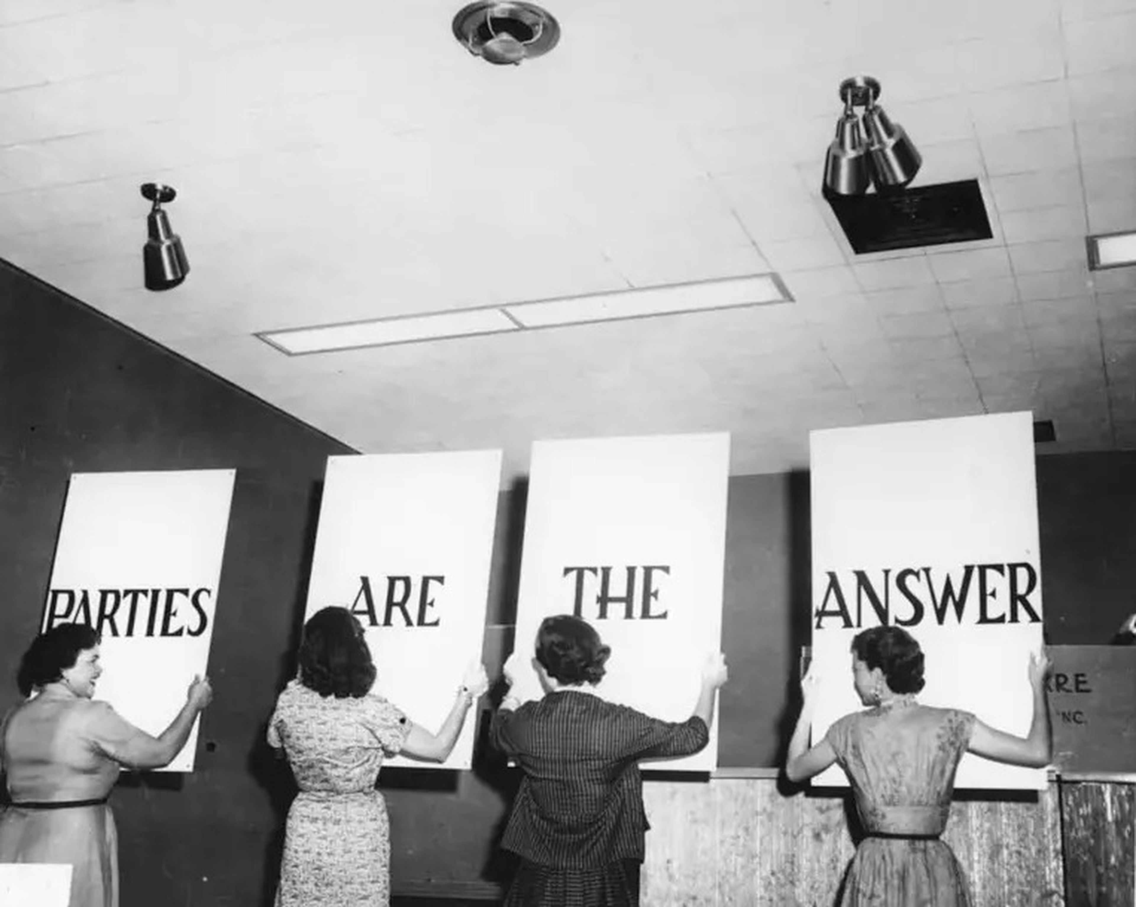 Tupperware hosts hold signs that read "Parties are the answer"