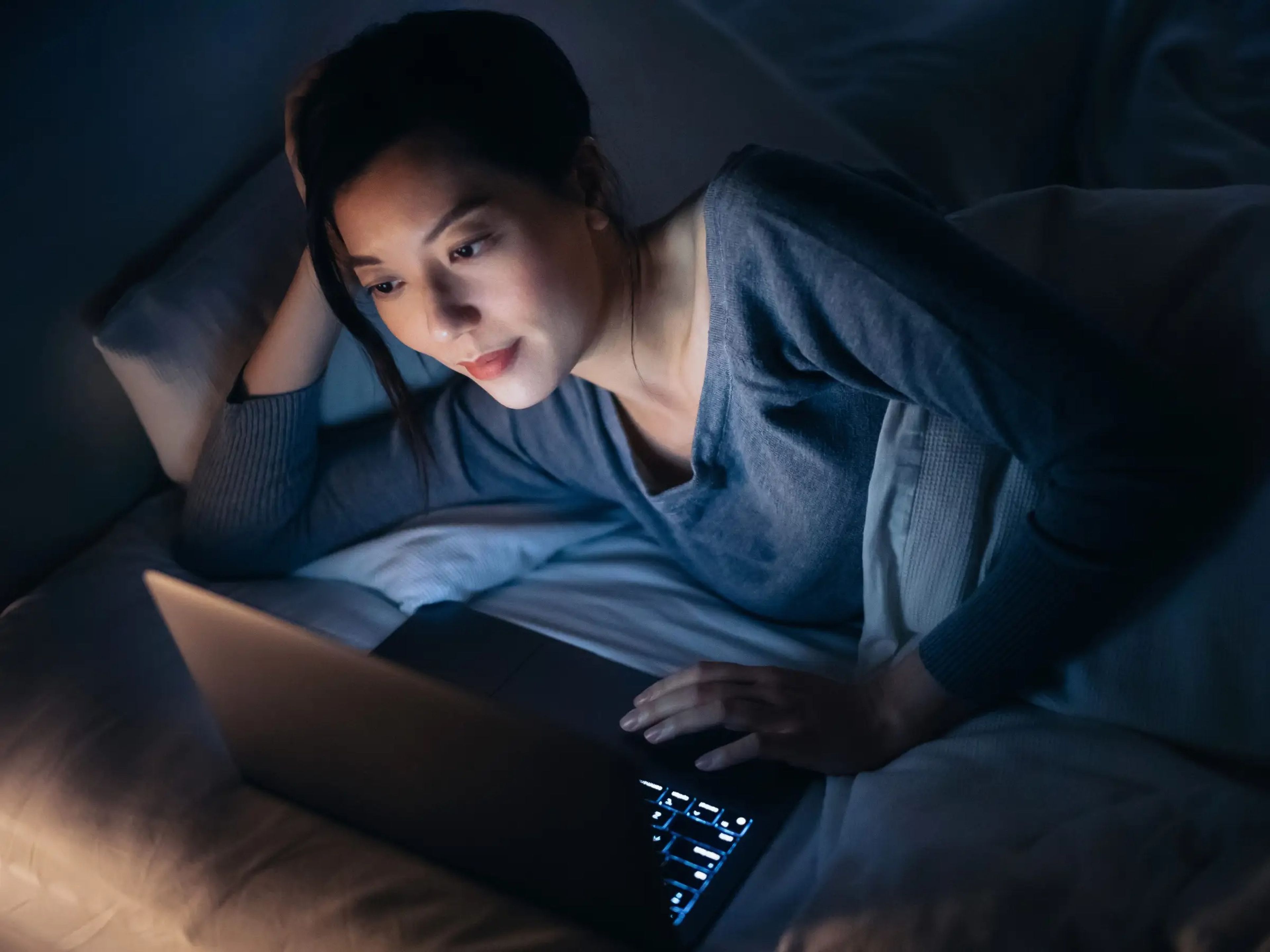 Woman using laptop in bed