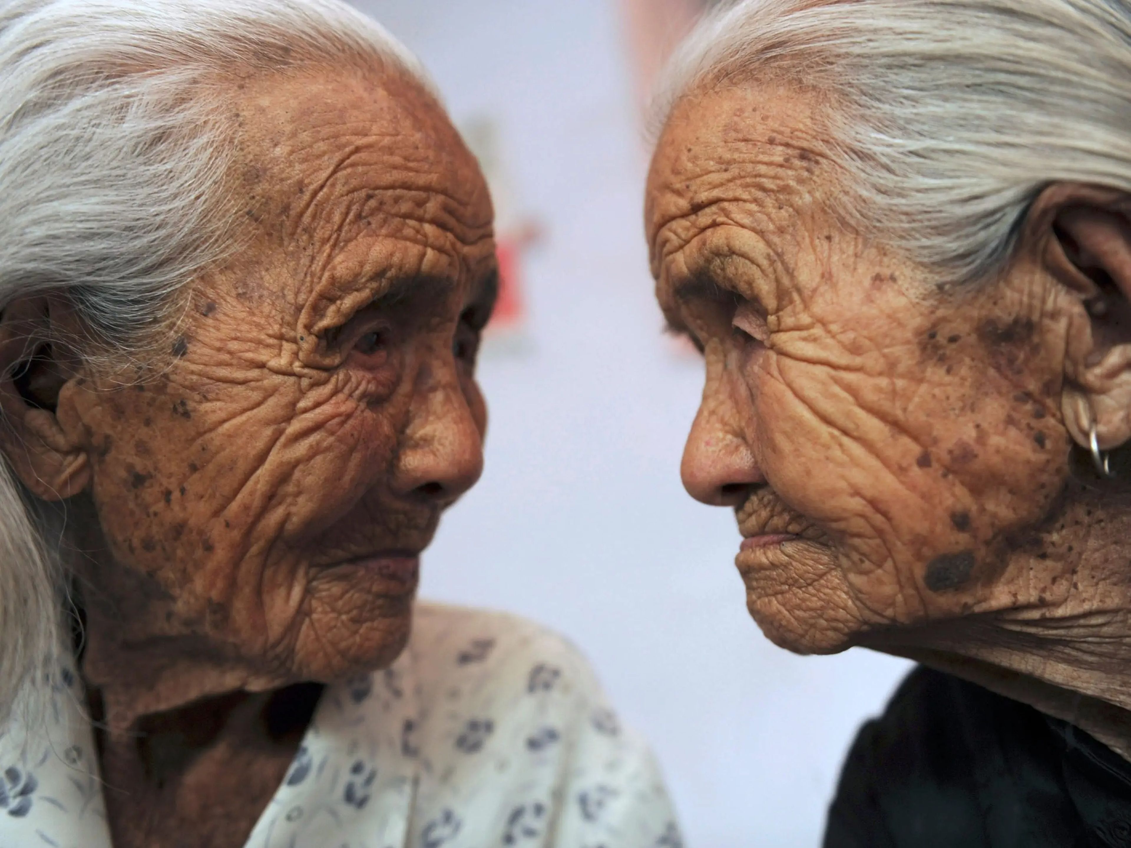 The Chinese twins looking at each other with their faces close together.