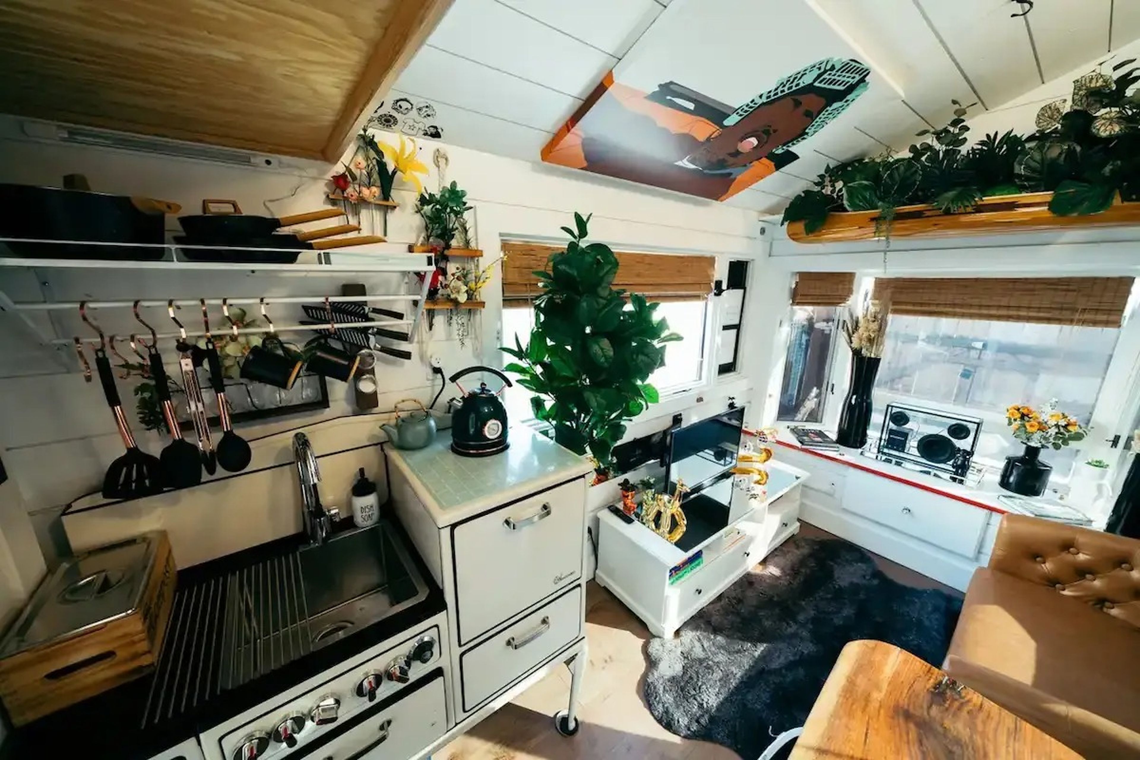 The kitchen space in Ansel Troy's Airbnb with cooking utensils on a rack and a living space off to the side.