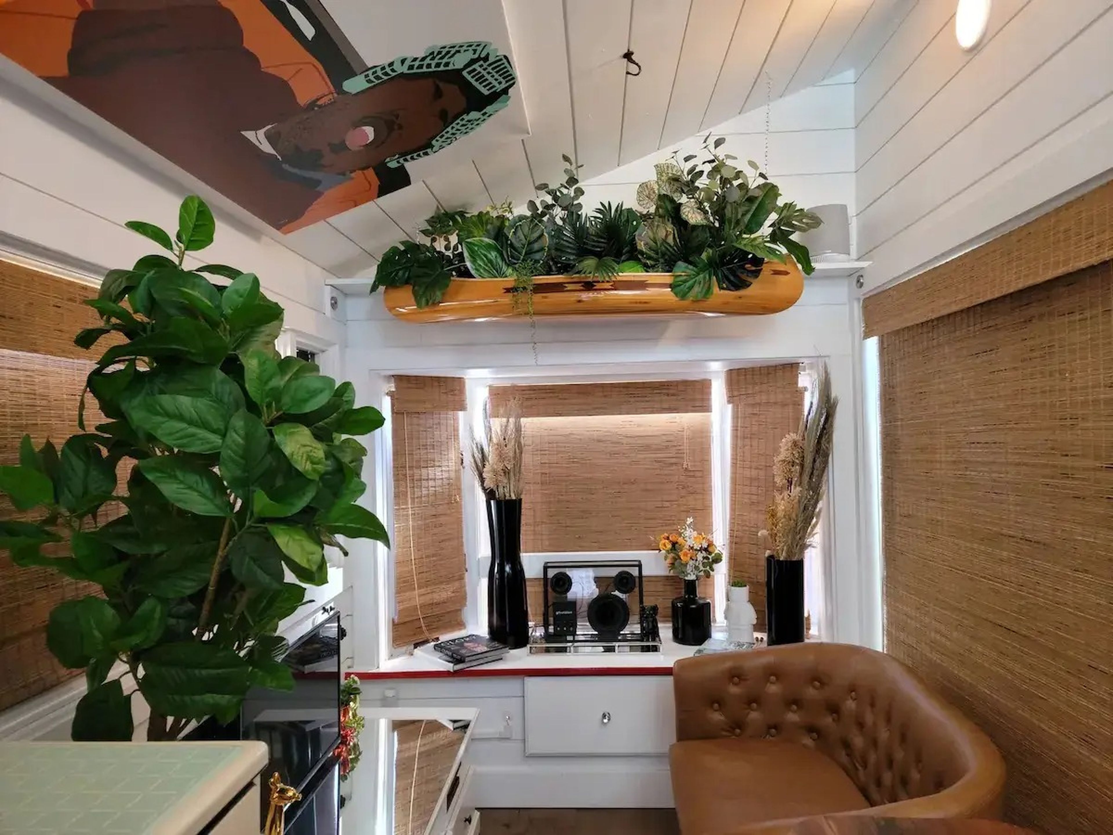 The living space in Ansel Troy's Airbnb with potted plants and a small couch in front of a TV.