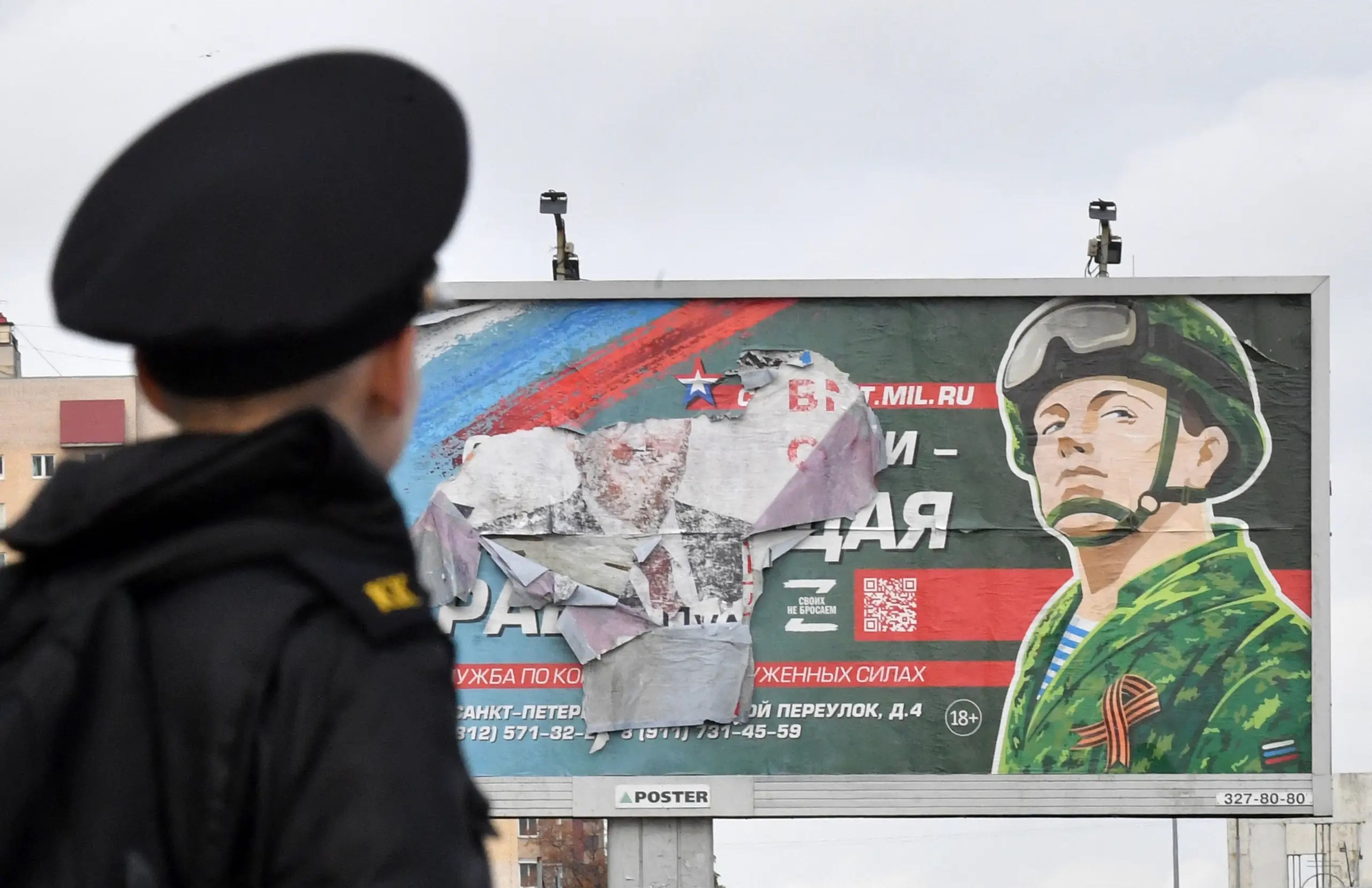 Un militar frente a una valla publicitaria que promociona el servicio militar en San Petersburgo.