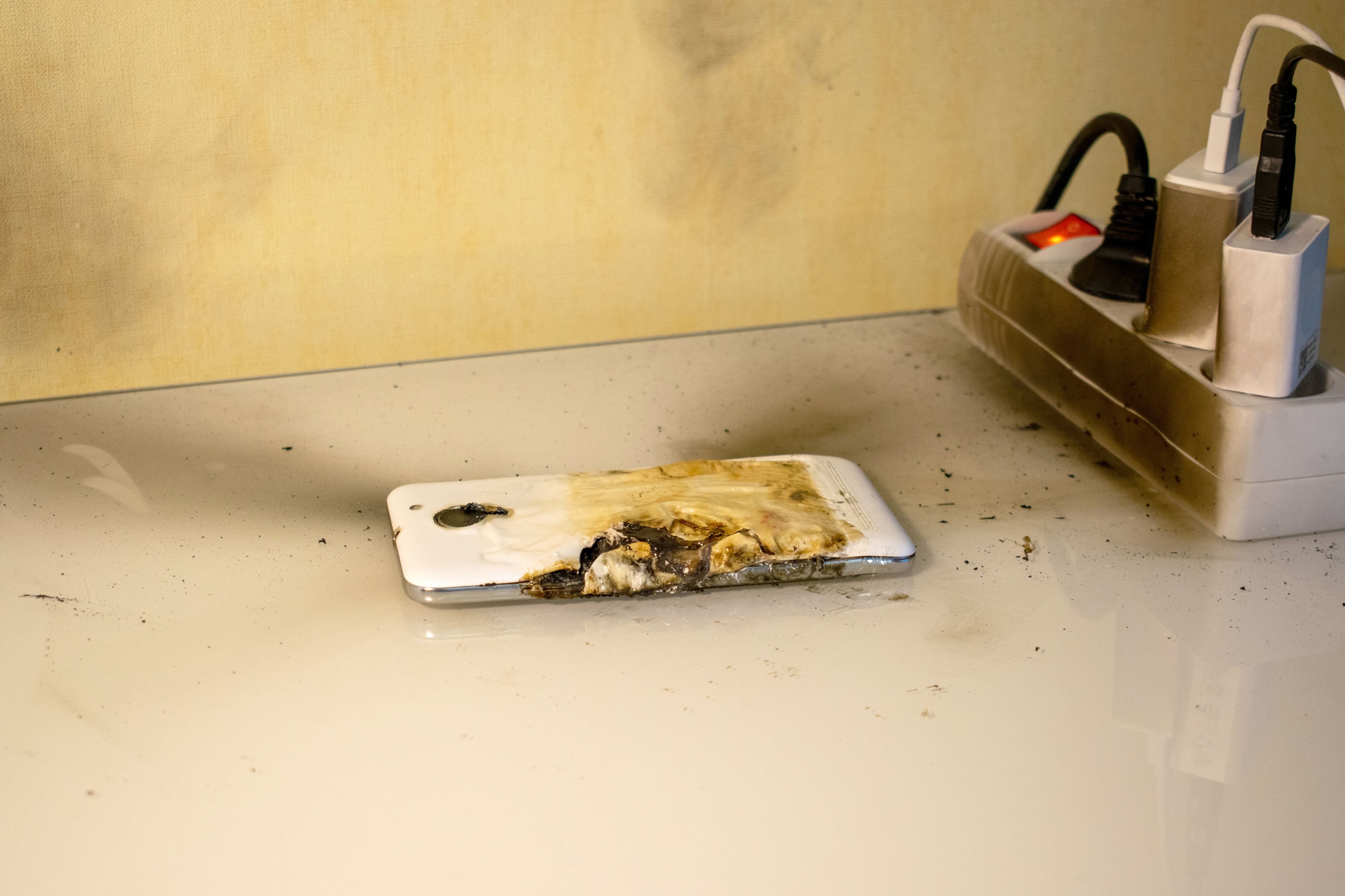 Un móvil y una regleta de enchufes que se ha quemado.