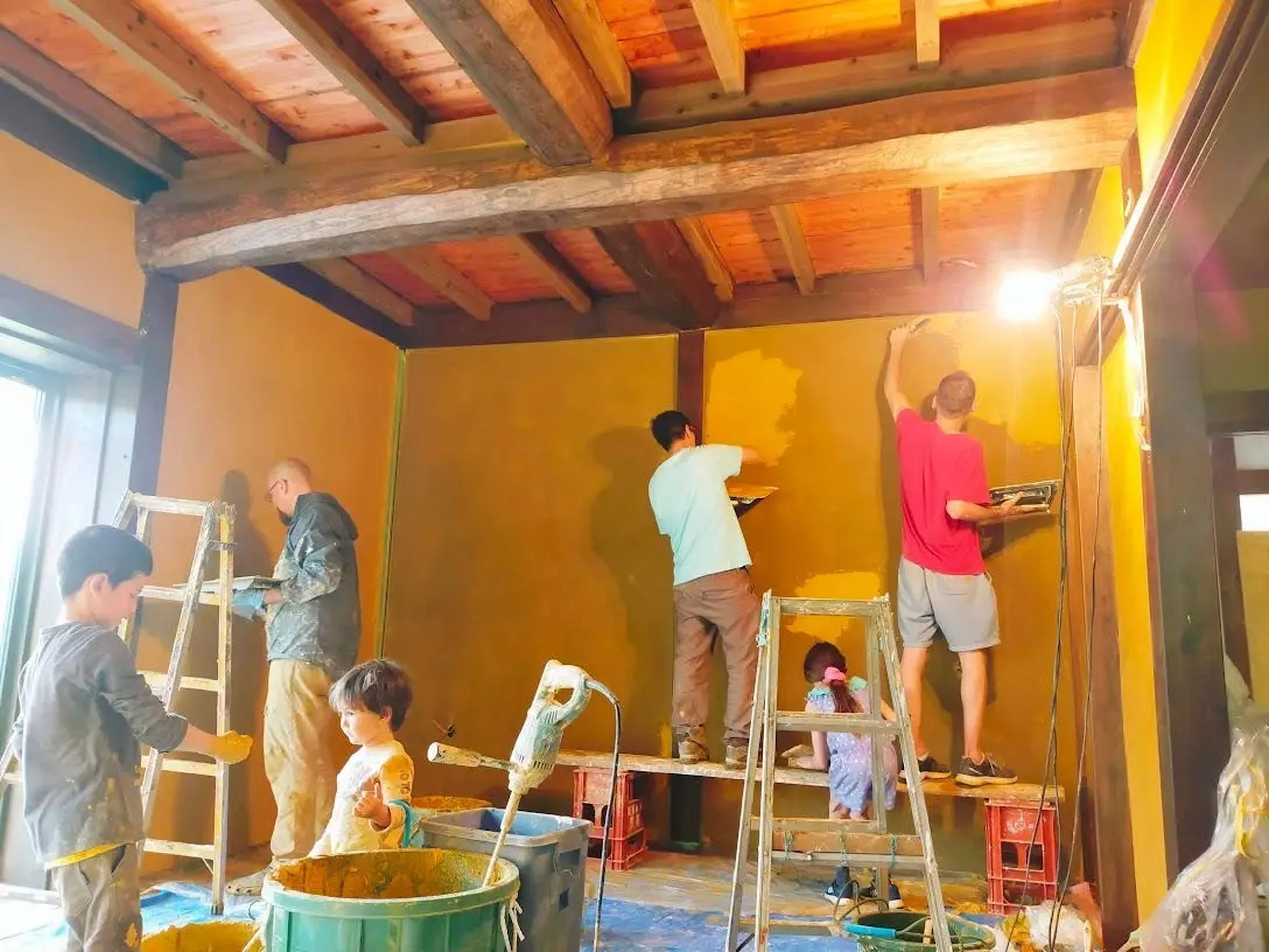 La familia Nagy y sus amigos renovando las paredes de un dormitorio de su casa.