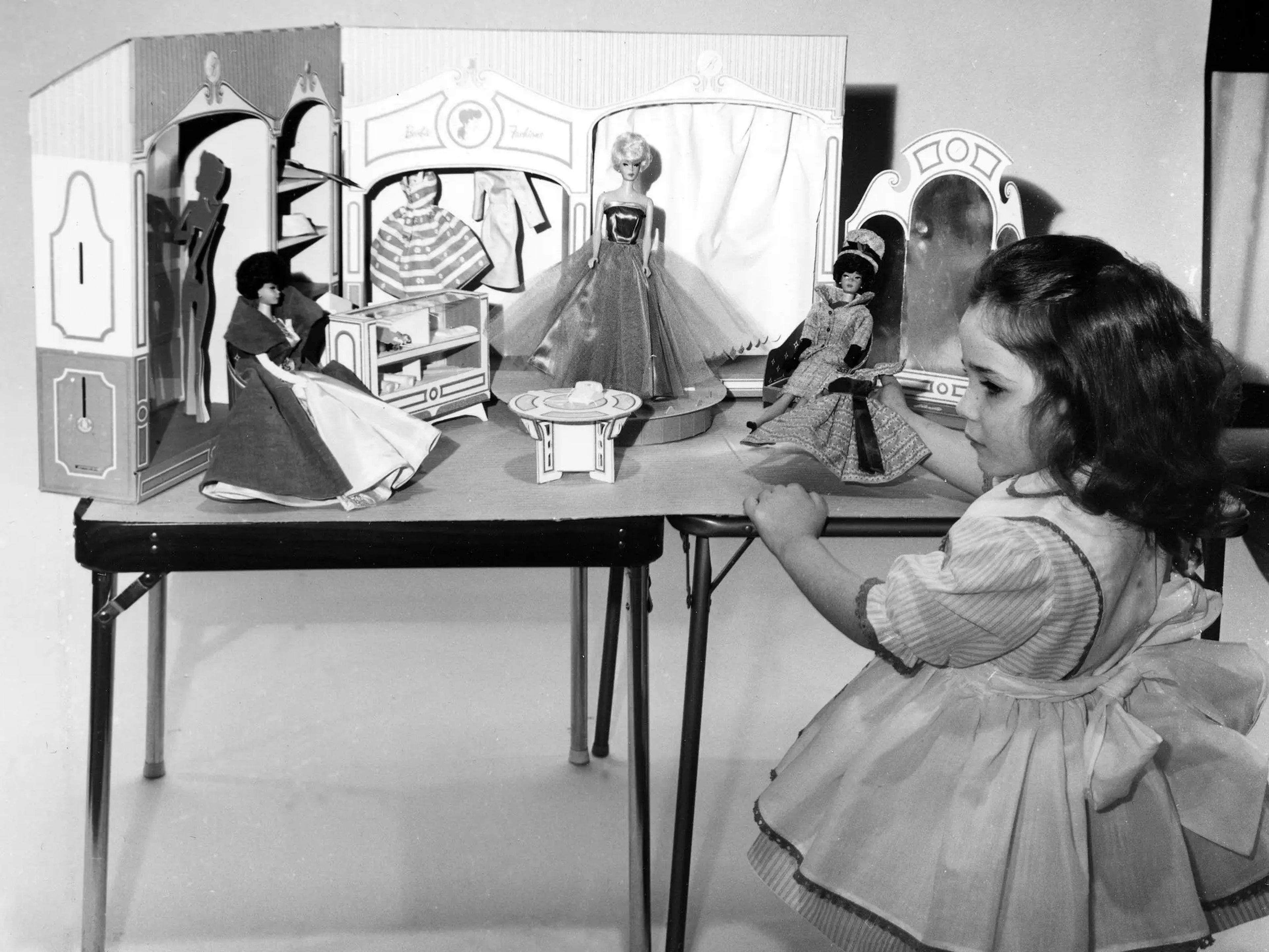 Una niña jugando con muñecas Barbie en 1963.