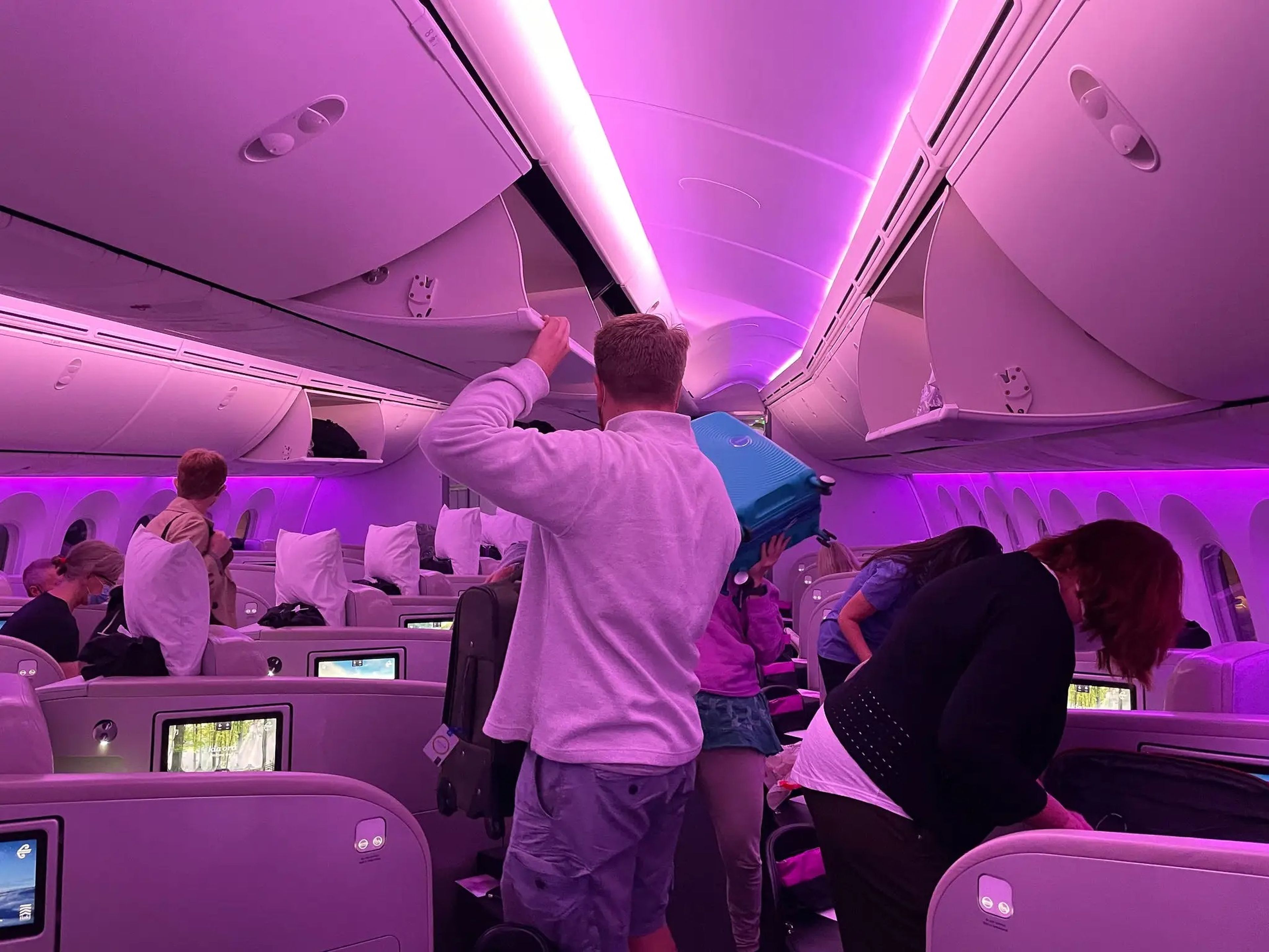 Passengers on a business class flight get their bags from the overhead bins.