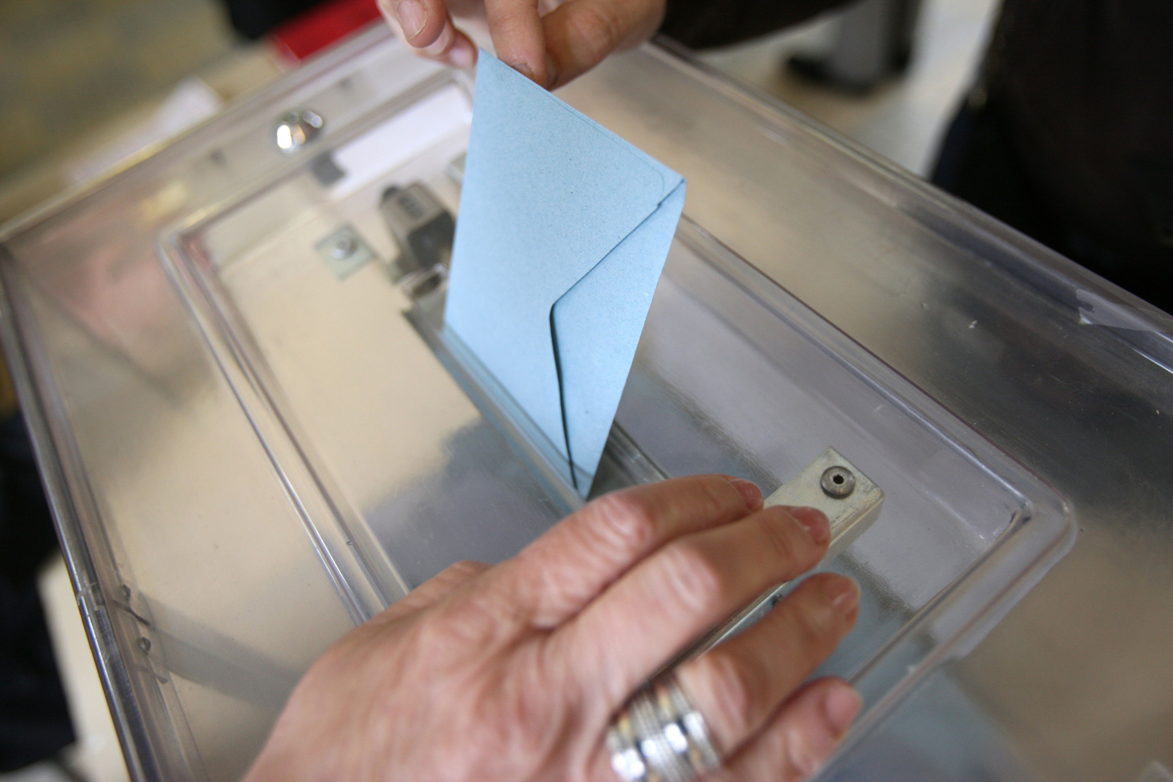 Una persona introduce el voto en la urna. 