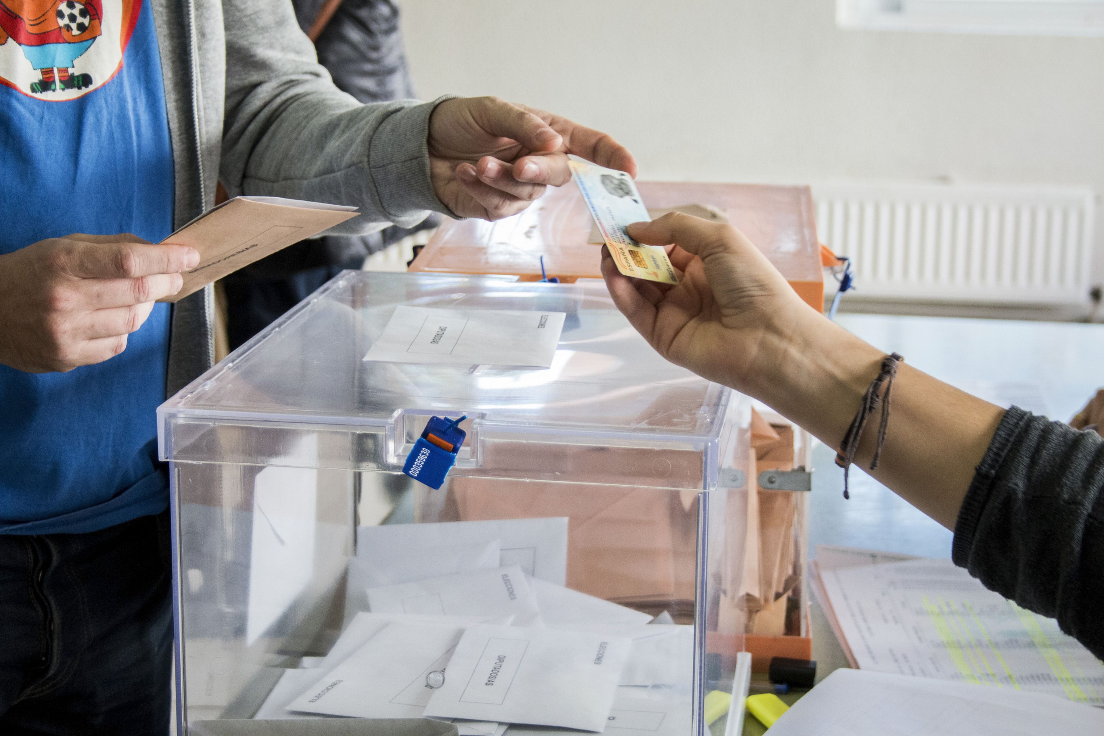 Una persona introduce su voto en una urna: elecciones en España