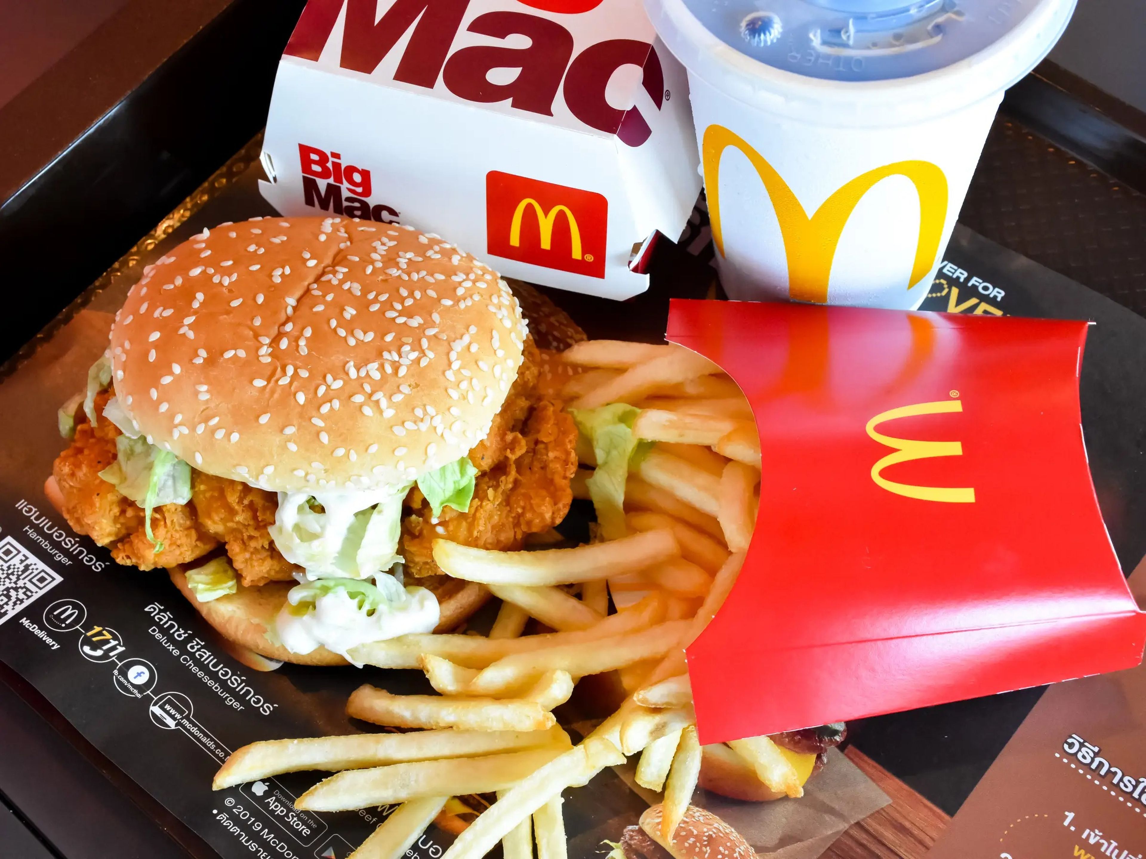 A chicken sandwich, french fries, a Big Mac box, and a soda on a tray.